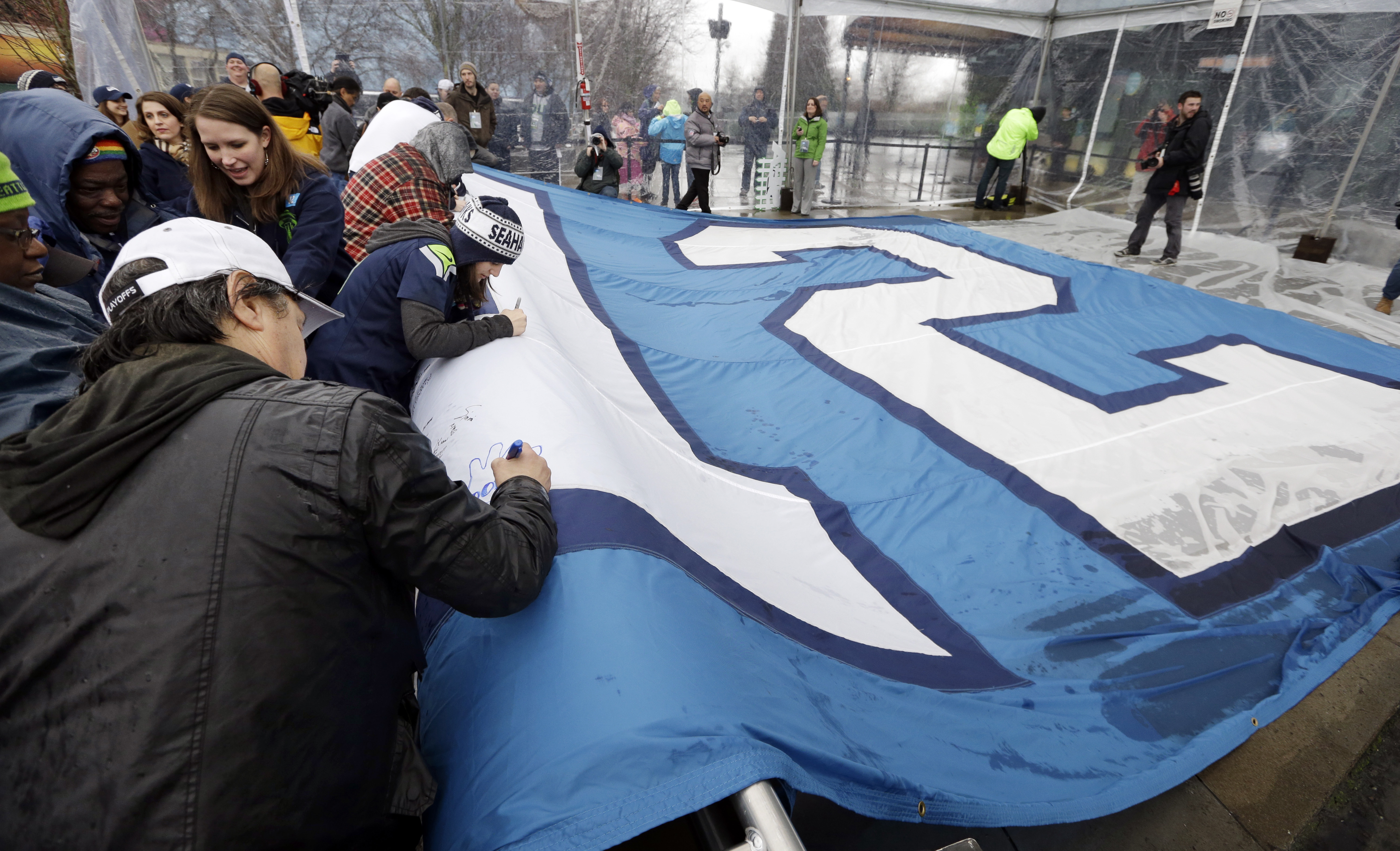 Seattle Seahawks fans sign a 25-foot by 35-foot 12th Man flag today at the base of the Space Needle in Seattle. The flag