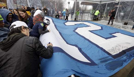 Seattle Seahawks fans sign a 25-foot by 35-foot 12th Man flag Wednesday near the Space Needle in Seattle. The Associated Press