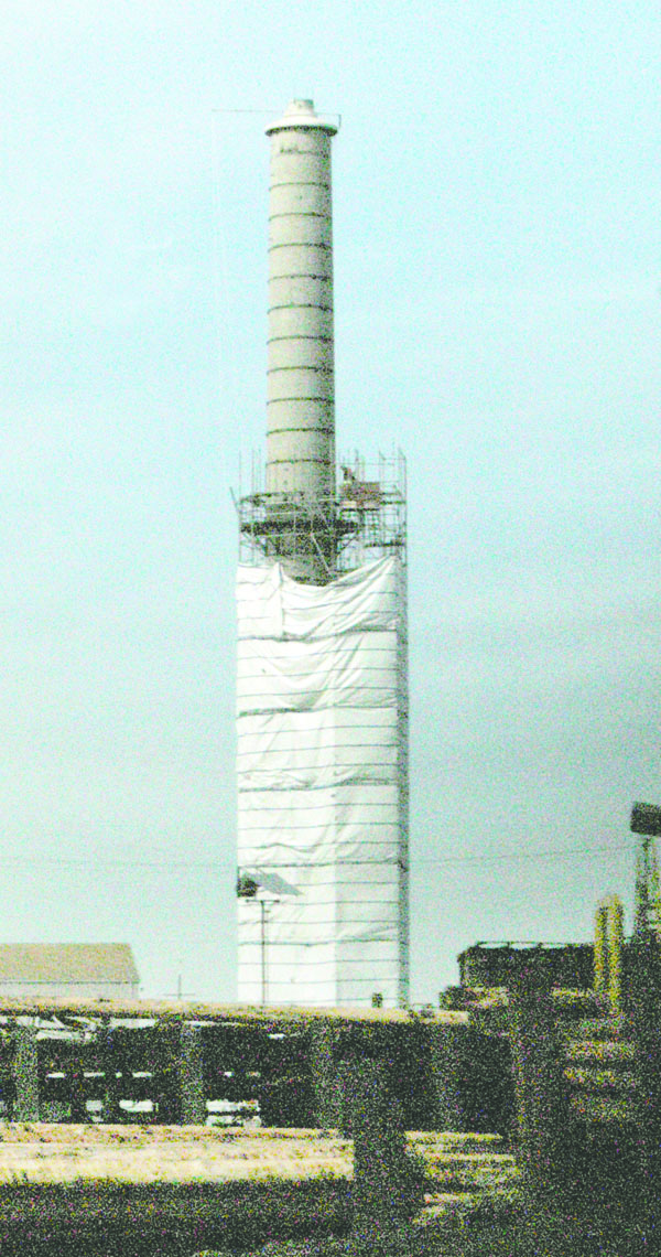 The smokestack that once serviced the now-razed plywood mill in Port Angeles slowly reappears from the plastic cocoon that shrouded it while its asbestos-laden surface was removed. Paul Gottlieb/Peninsula Daily News