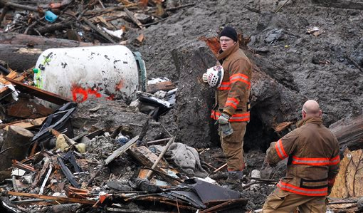 Searchers pause for a moment of silence at the scene of the deadly mudslide. The Associated Press (click on photo to enlarge)