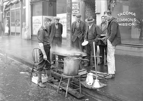 Men using a wheelbarrow as a makeshift stove are captured in Chapin Bowen's photo “Breakfast Outside the Tacoma Commons Mission