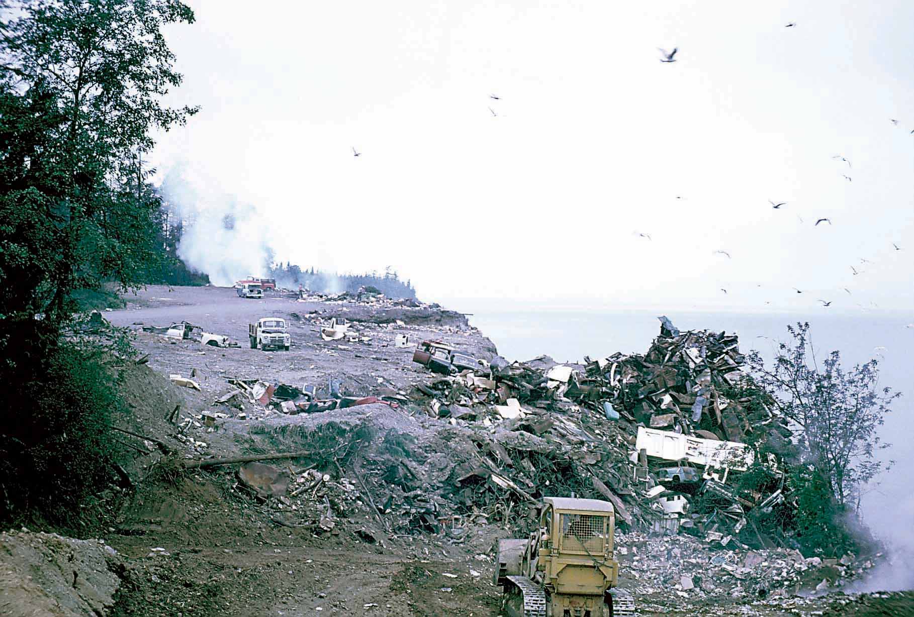 Photo circa 1960 from Port Angeles city archives show a bulldozer pushing trash over the bluff onto the Strait of Juan de Fuca beach below.