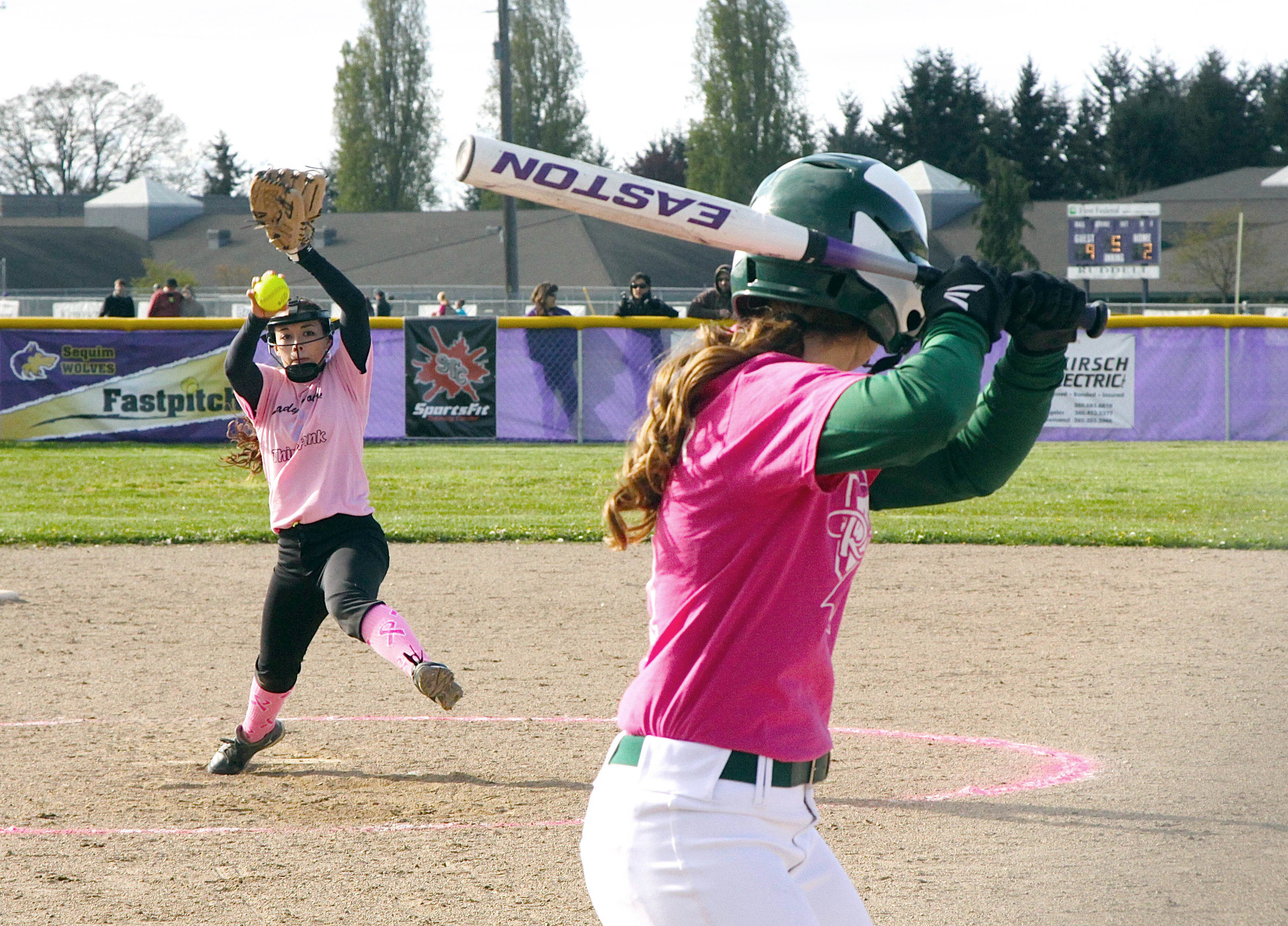 Sequim pitcher Makayla Bentz winds up to deliver to Port Angeles batter Tori Kuch. The Roughriders got the best of their rivals in a 5-0 win. The two teams wore pink uniforms in an effort to promote cancer awareness. Dave Logan/for Peninsula Daily News