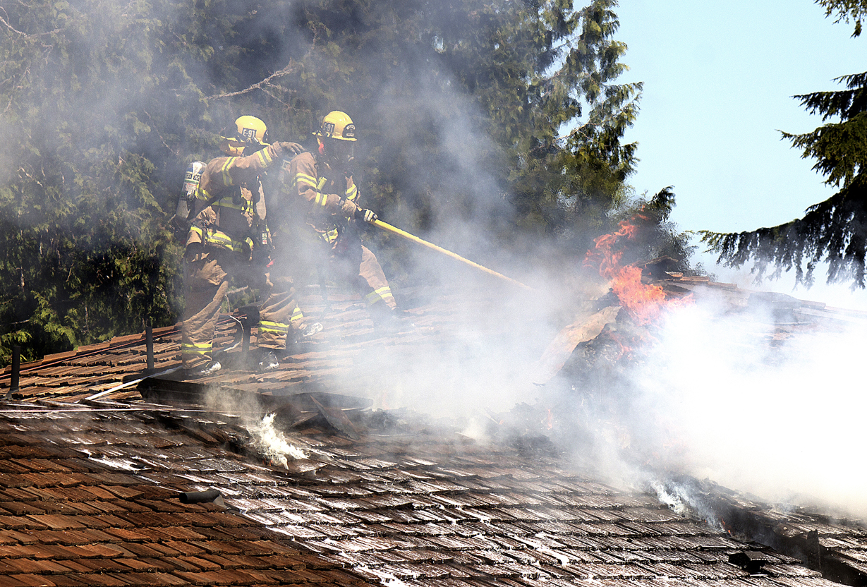Port Ludlow firefighters fight a roof blaze at a home on Condon Lane on Tuesday. Sheila L. George
