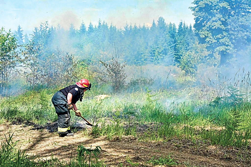 Lt. Patty Reifenstahl of Clallam County Fire District No. 2 digs a line around a grass fire in the Black Diamond area south of Port Angeles on Tuesday. Jay Cline/Clallam County Fire District No. 2
