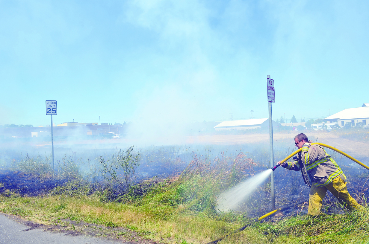 Firefighters extinguish a blaze in a grassy field Wednesday afternoon in Sequim. Clallam County District No. 3