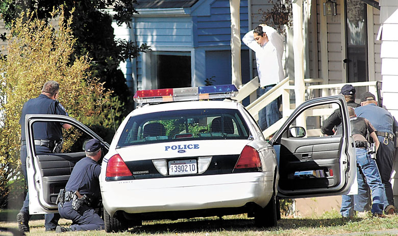 Port Angeles police watch as a man wanted on a federal arrest warrant emerges from a house in the 400 block of East Sixth Street in Port Angeles in 2009. Keith Thorpe/Peninsula Daily News