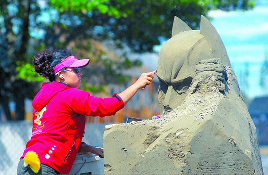 Sue McGrew of Tacoma carves the visage of Batman for the Windermere Sand Sculpture Classic in Port Angeles. The event is part of the larger Arts in Action festival taking place throughout downtown and City Pier this weekend. Keith Thorpe/Peninsula Daily News