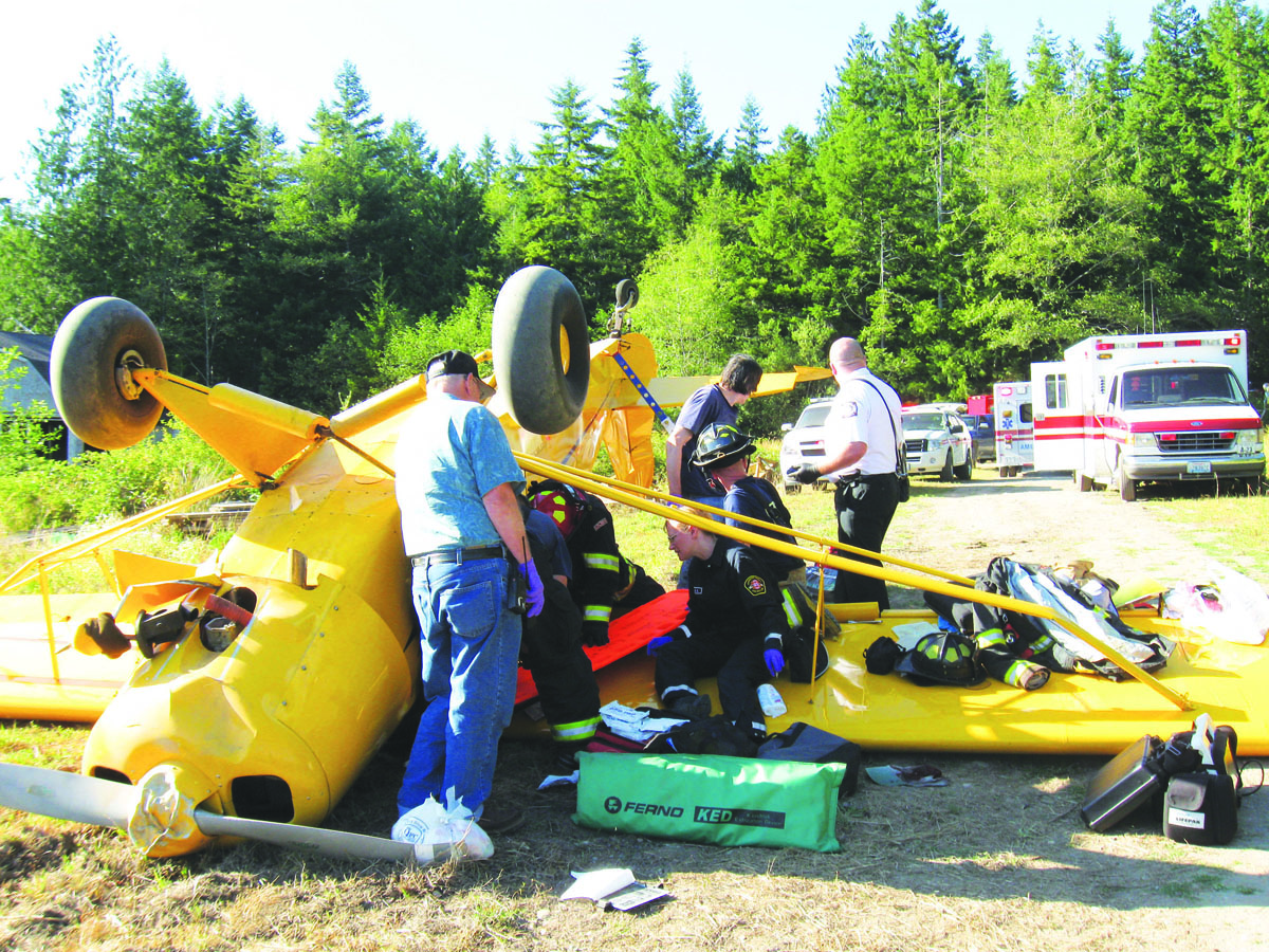 Emergency responders gather around the Piper Super Cub that flipped during an attempted landing Saturday in Quilcene. Jefferson County Sheriff's Office