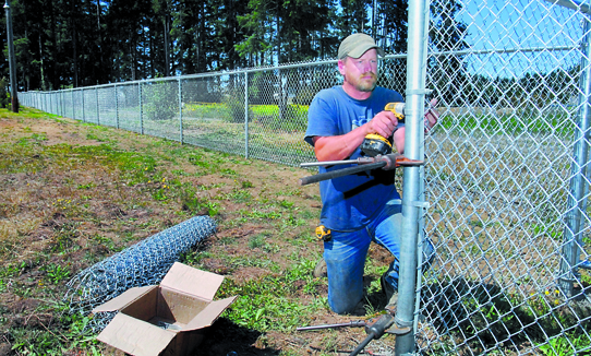 Chad Lund of Lund Fencing of Carlsborg attaches chain link to a corner post at the free-run dog park due to open at Lincoln Park in Port Angeles. Keith Thorpe/Peninsula Daily News