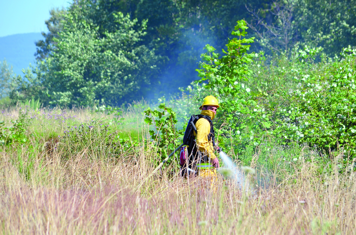 Firefighter-paramedic Len Horst of Clallam County Fire District No. 3 sprays water on a grass fire between U.S. Highway 101 and the new Black Bear Diner in Sequim. Clallam County Fire District No. 3