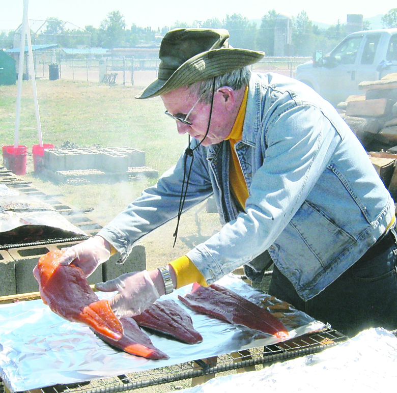 Sequim Rotarian Peter Bahnsen prepares fresh salmon filets for the alder wood fire grill at a previous salmon bake. Rotary Club of Sequim