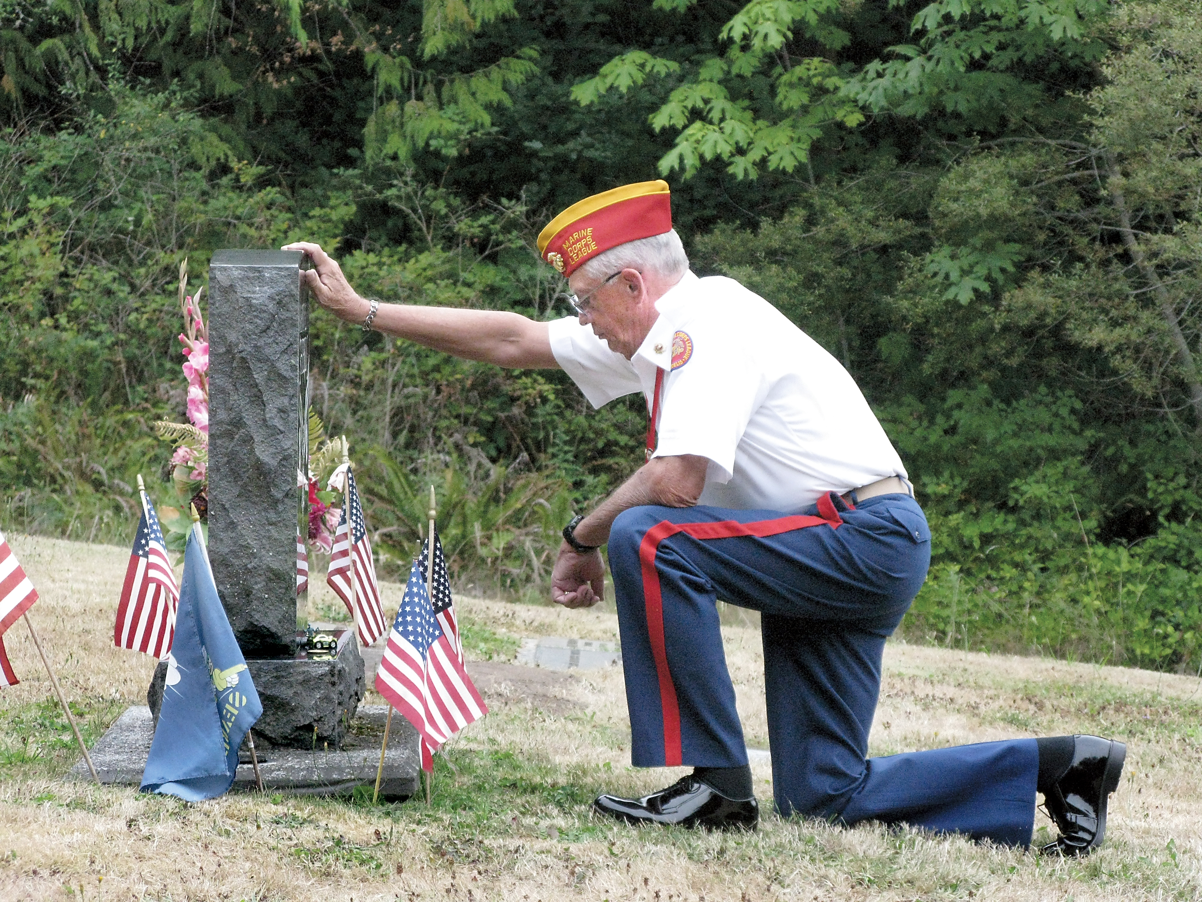 Vietnam Marine Corps veteran Mark Schildknecht leaves a challenge coin on the Gardiner Cemetery grave of Marvin Shields