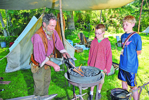 A reenactor shows two boys how things were done way back when at the annual Green River Mountain Men rendezvous in 2011. Peninsula Daily News Staff File Photo