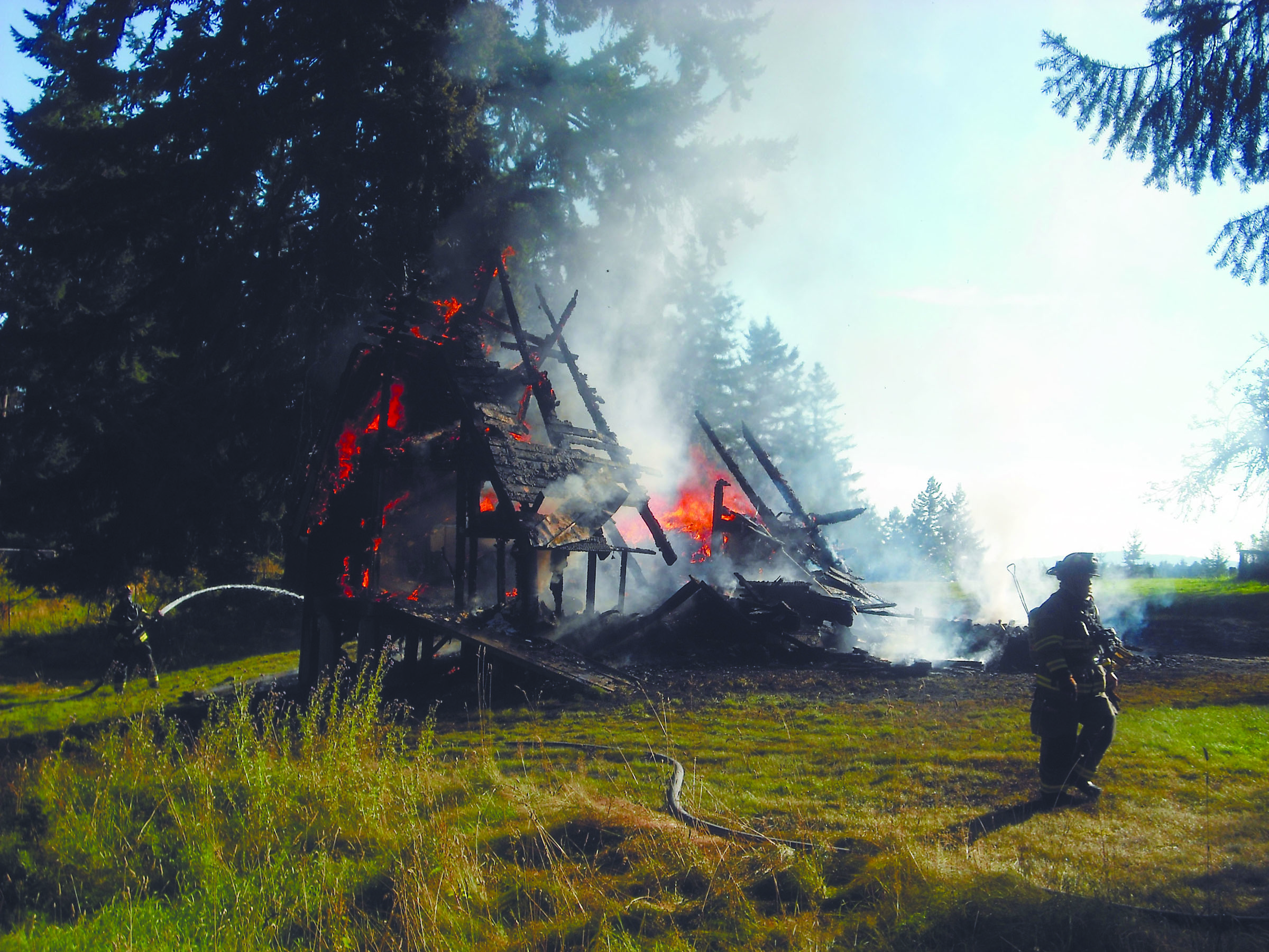 Flames ravage the remains of the Deer Park Road A-frame. Margaret McKenzie/Peninsula Daily News