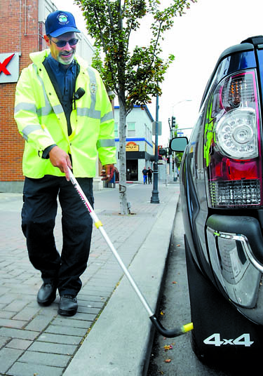 Port Angeles parking control officer Glenn McFall puts a chalk mark on the tire of a vehicle in downtown Port Angeles on Friday. Keith Thorpe/Peninsula Daily News