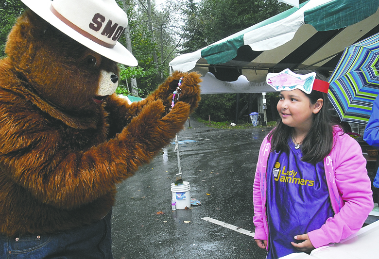 Kyra Cartwright of Sequim watches as Smokey Bear looks at a string of beads Kyra created at an activity booth set up by the Olympic Driftwood Sculptors group at the annual Dungeness River Festival in 2013 at Railroad Bridge Park near Sequim. The event featured a variety of exhibits and activities geared around nature
