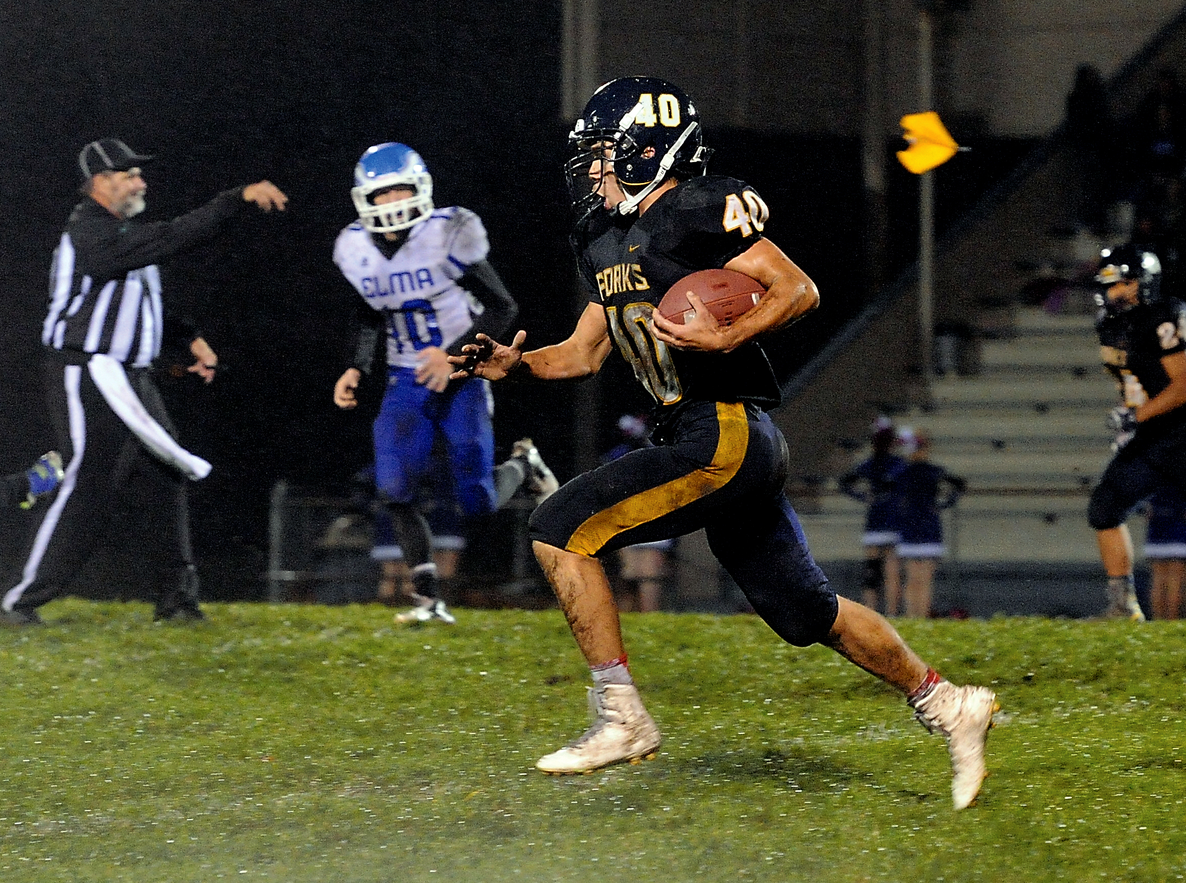 Forks running back Garrison Schumack (40) runs for a big gain that was called back due to a holding penalty as indicated by the flag in the background. Elma's Bryson Crisp (10) pursues Schumack from across the field. Lonnie Archibald/for Peninsula Daily News
