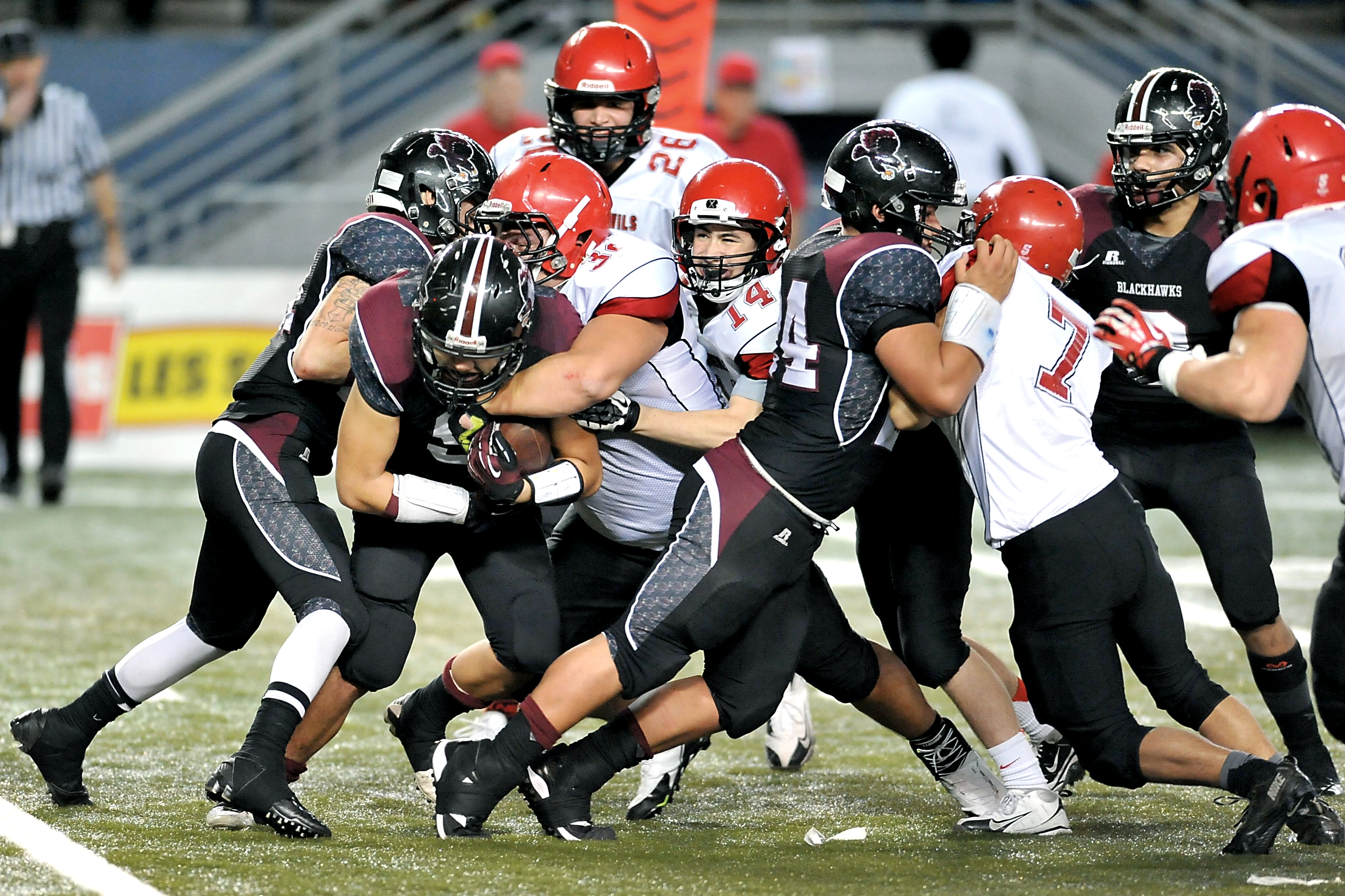 Neah Bay defenders Tyler McCaulley (32) and Cameron Buzzell (14) tackle Lummi running back Devin Cooper with help from Bobby Long Jr. (7) and Ezekiel Greene (26) during the 1B state semifinal at the Tacoma Dome. Jeff Halstead/for Peninsula Daily News