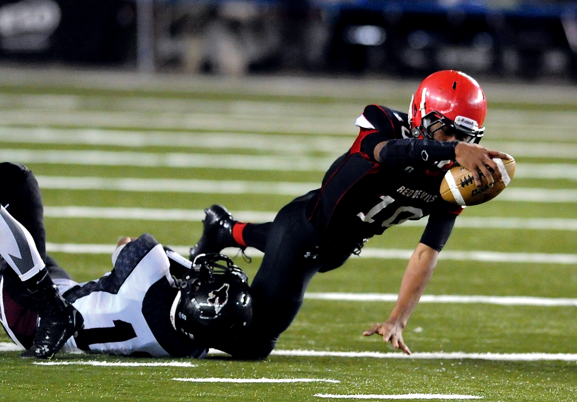 Neah Bay's Rwehabura Munyagi Jr. reaches for extra yards after being brought down by Lummi's Free Borsey during the Red Devils 26-20 loss in the state semifinals. Jeff Halstead/for Peninsula Daily News