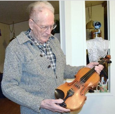 Pearl Harbor survivor Tom Berg holds the violin that he had in his possession on Dec. 7
