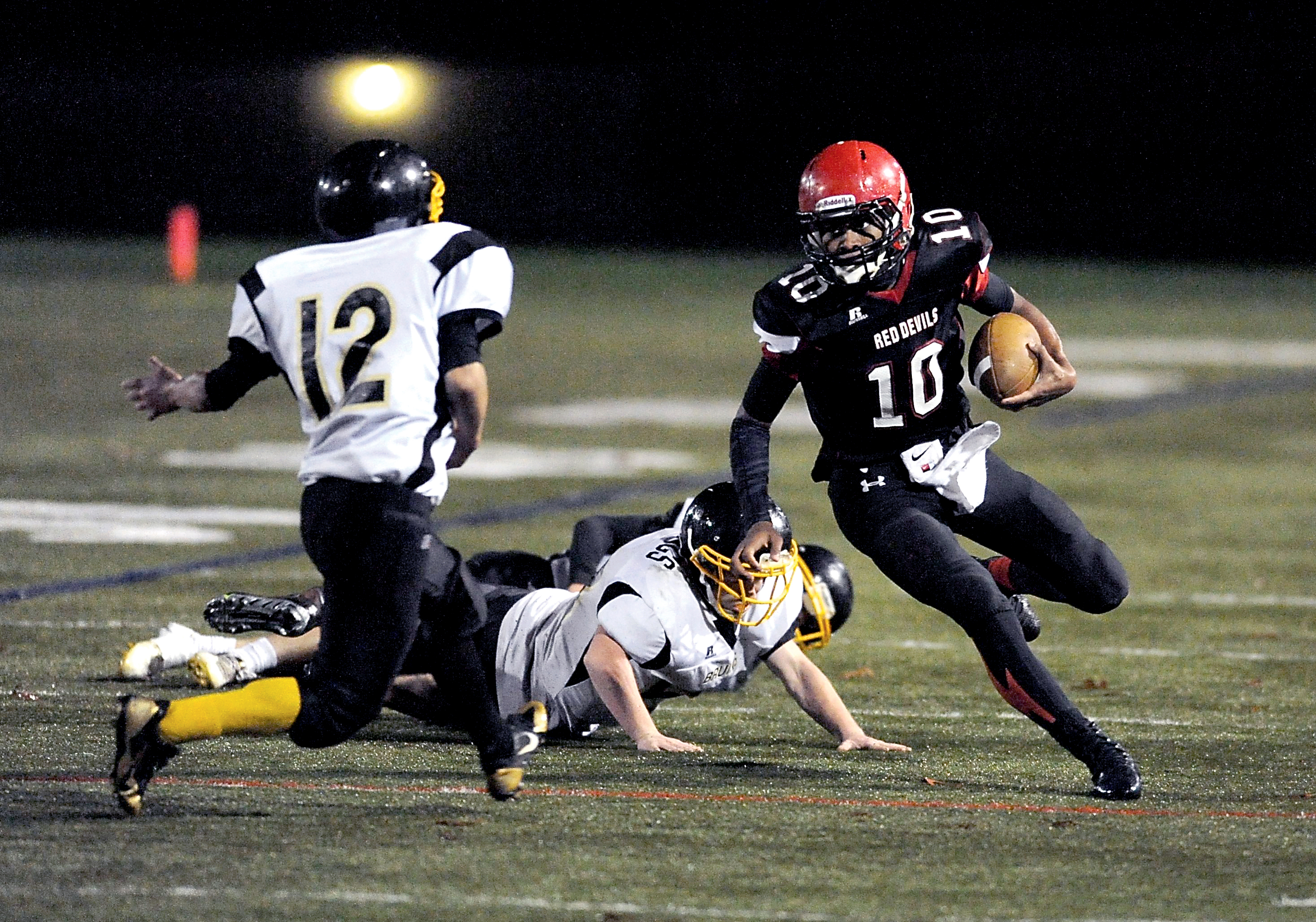 Neah Bay's Rwehabura Munyagi Jr. makes a cut that will get him past Ramon Tinoco (12) during his 33-yard touchdown run in the fourth quarter of the Red Devils' 68-0 state-playoff win over Clallam Bay. Jeff Halstead/for Peninsula Daily News