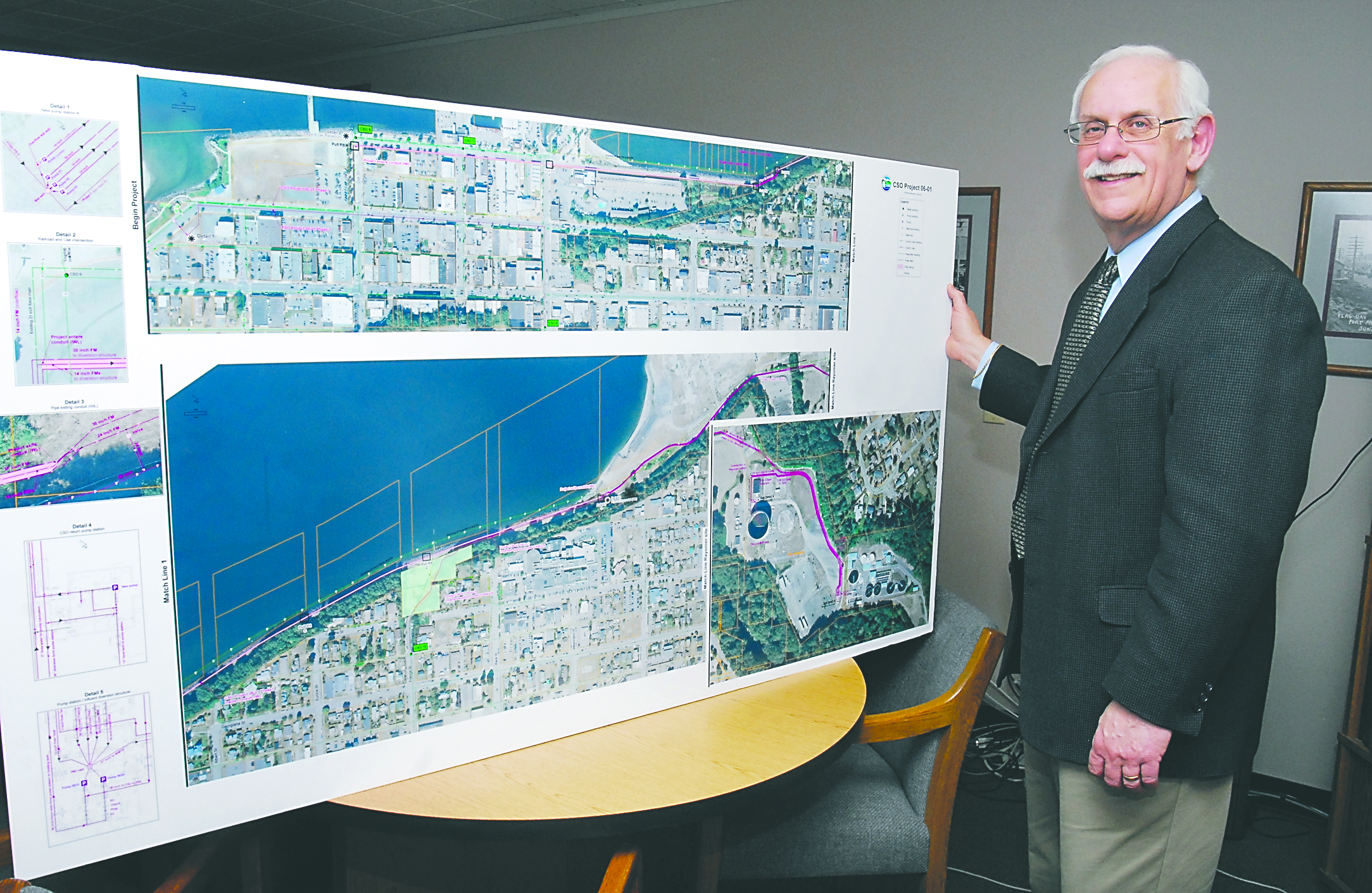 Public Works and Utilities Director Glenn Cutler stands with a display at City Hall showing an aerial schematic diagram of the city’s combined sewer outflow project