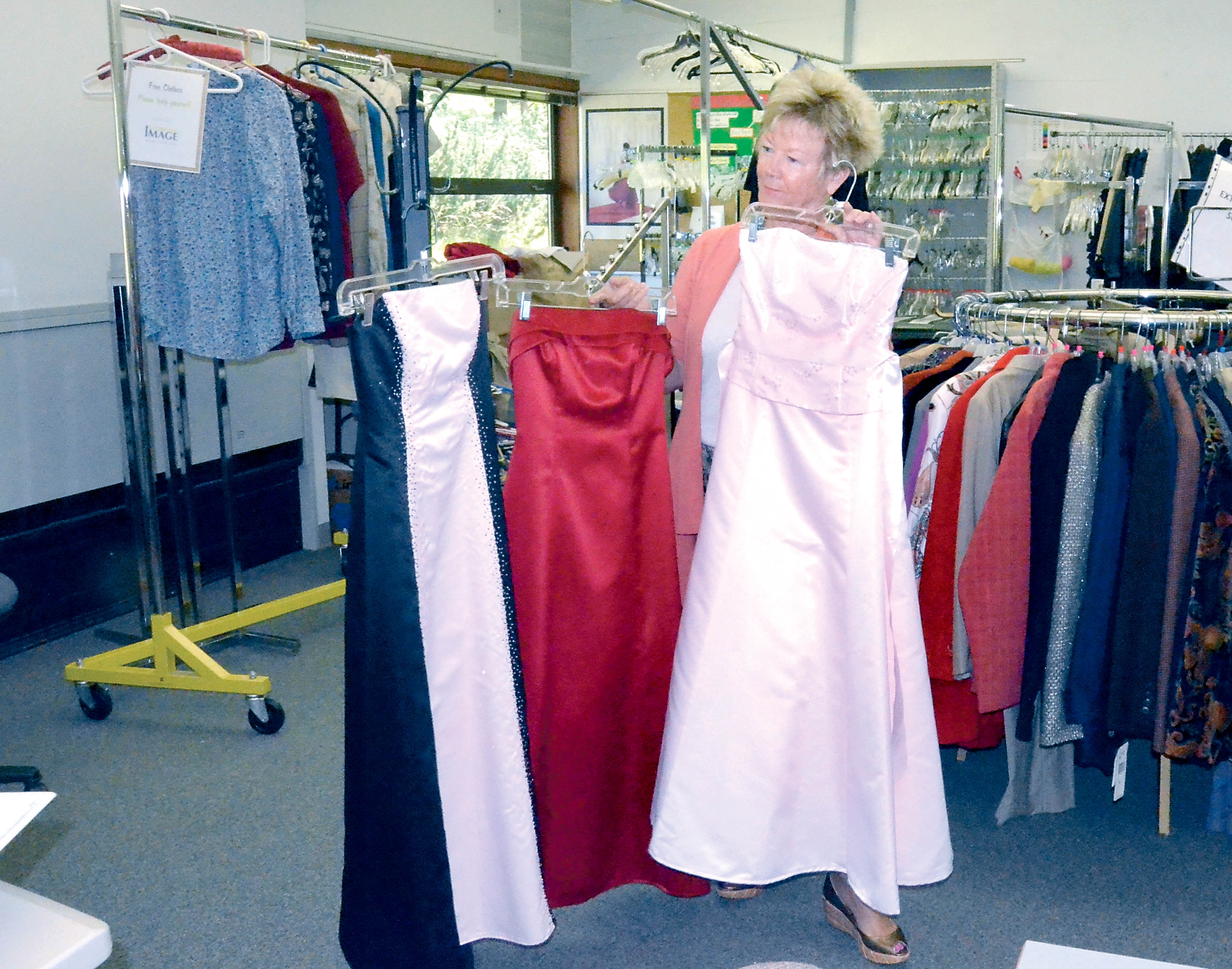Working Image President Lisa Hickman goes over three of the formal dresses in Cinderella’s Closet.  —Photo by Charlie Bermant/Peninsula Daily News