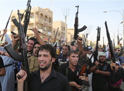 Shiite tribal fighters raise their weapons and chant slogans against the al-Qaida-inspired Islamic State of Iraq and the Levant (ISIL) in northwest Baghdad’s Shula neighborhood today. Sunni militants captured a key northern Iraqi town along the highway to Syria early Monday