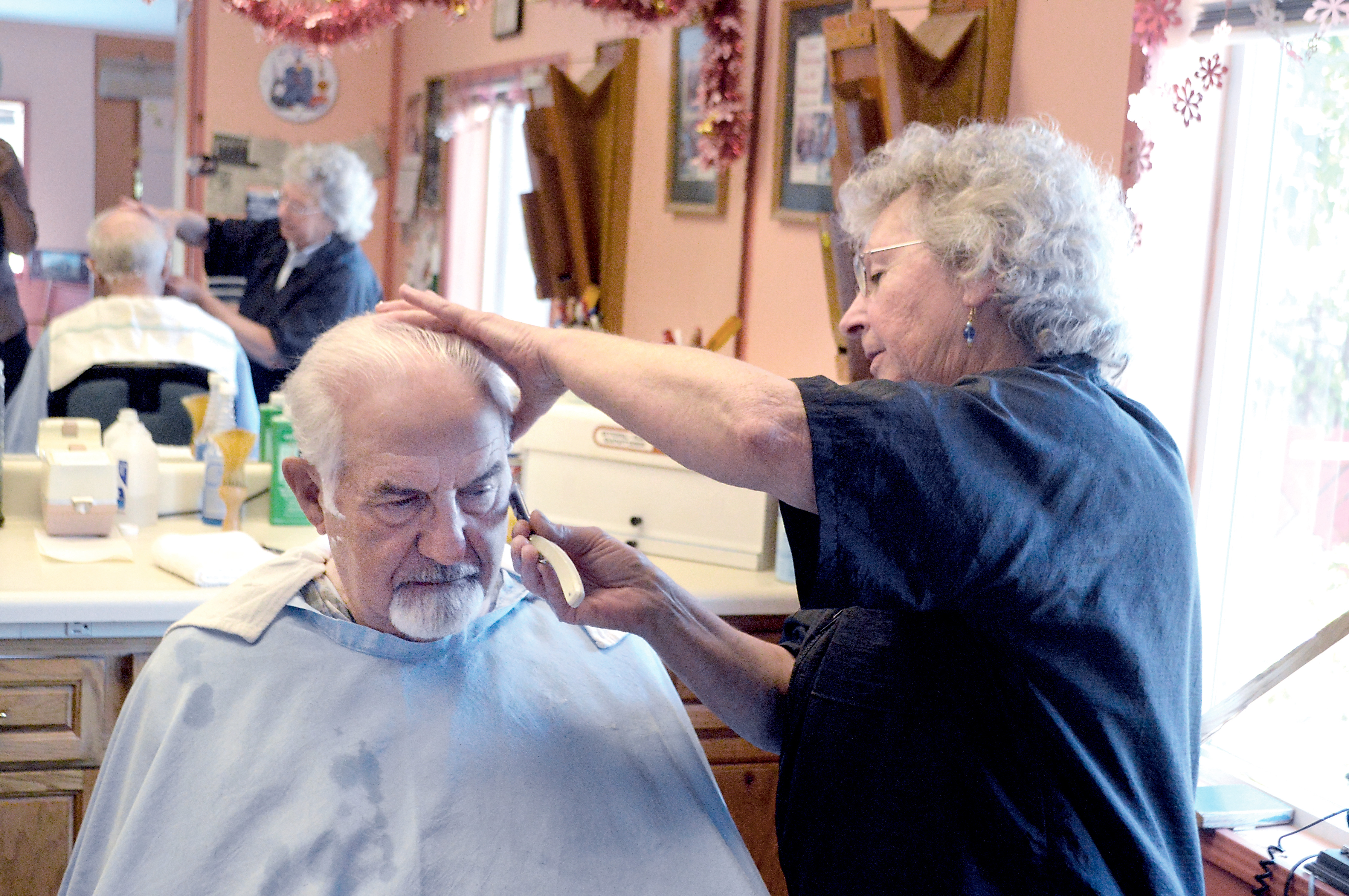 Carlsborg barber Joyce Horner shaves Bob Hicks' neck Tuesday. One of the last barbers on the North Olympic Peninsula to still offer hot shaves
