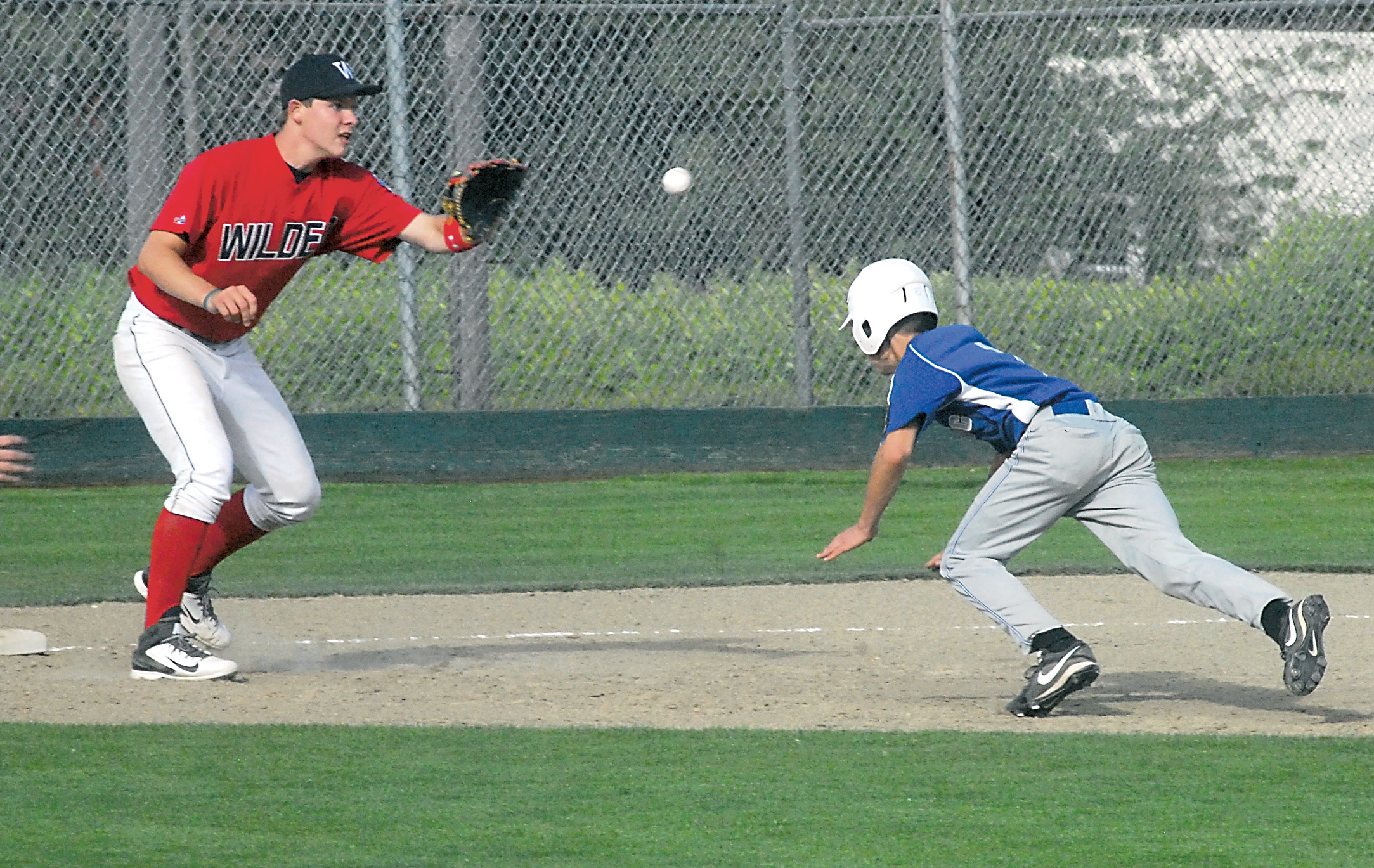 Wilder shortstop Dan Harker tries to cut off Olympic's Eric Turnquist at third base in the second inning of Wilder's 17-11 at Civic Field in Port Angeles. Keith Thorpe/Peninsula Daily News
