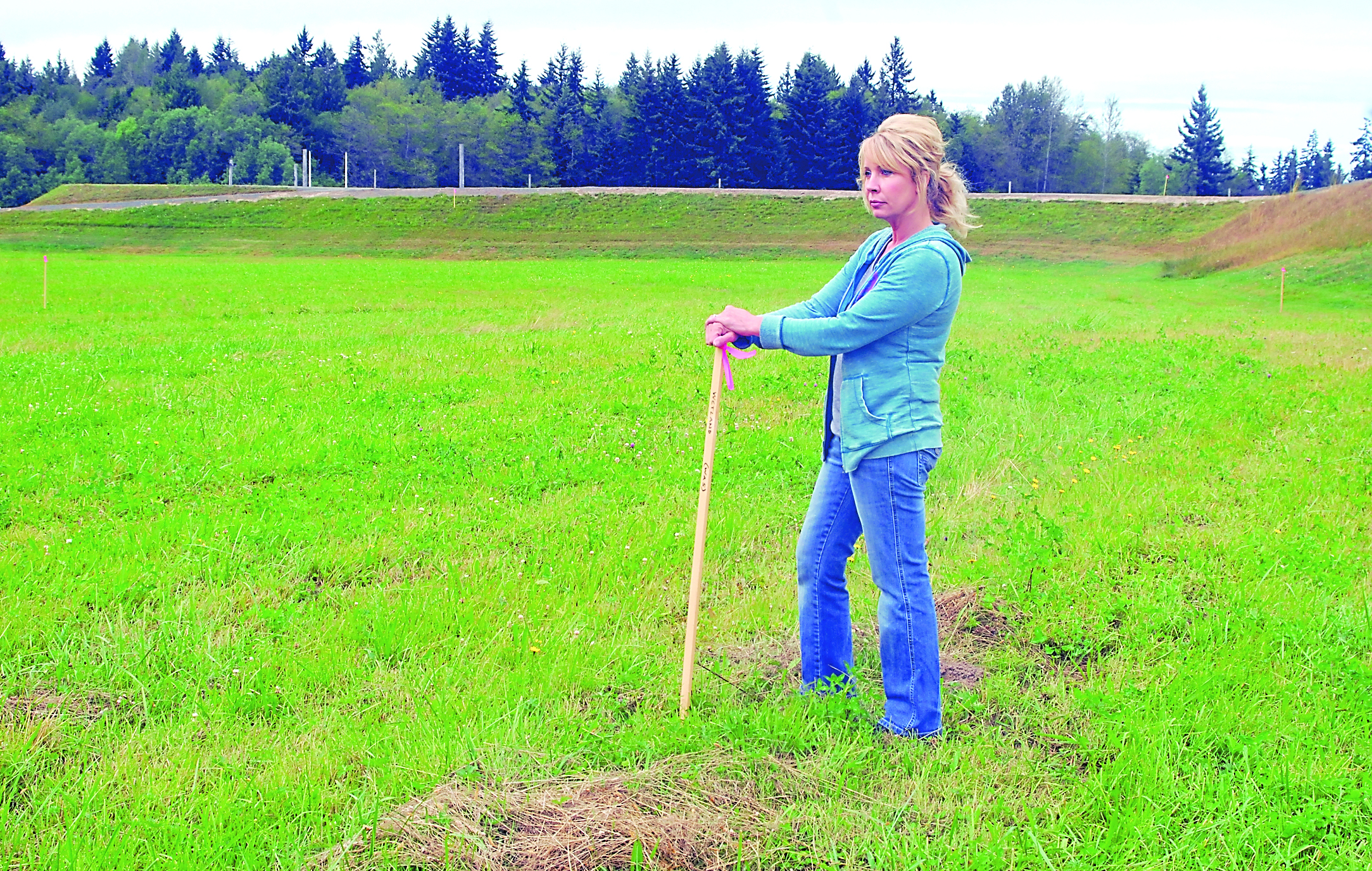 Kelie Morrison stands next to a stake marking the boundary of designated wetland next to the sprint boat track at the Extreme Sports Park on the west edge of Port Angeles — an area that is identical to topography outside the wetland zone.  -- Photo by Keith Thorpe/Peninsula Daily News