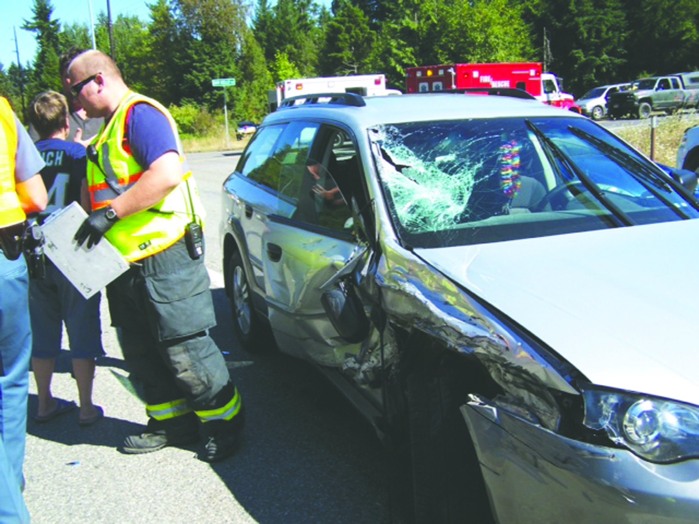 Emergency personnel from Clallam County Fire District discuss a two-vehicle crash that occurred Sunday afternoon at the intersection of Dan Kelly and Place roads with state Highway 112. Drivers of both vehicles were treated and released at the scene. — Clallam County Fire District No. 2