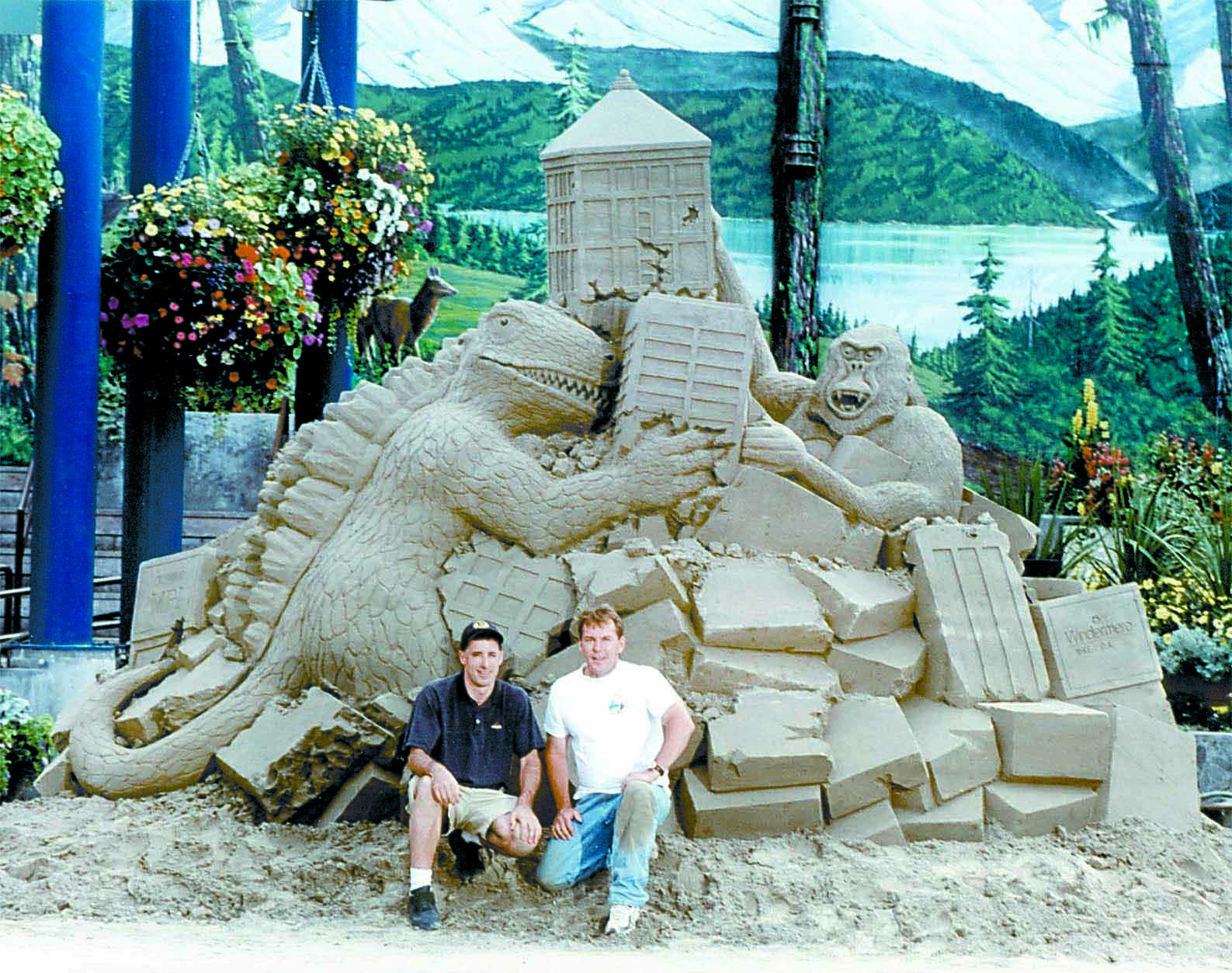 Sand sculptors Andrew Briggs of Victoria and Charlie Beaulieu of Kingston sit in front of their sand sculpture of Godzilla and King Kong at the Conrad Dyar Memorial Fountain in downtown Port Angeles in this August 2001 file photo. Keith Thorpe/Peninsula Daily News
