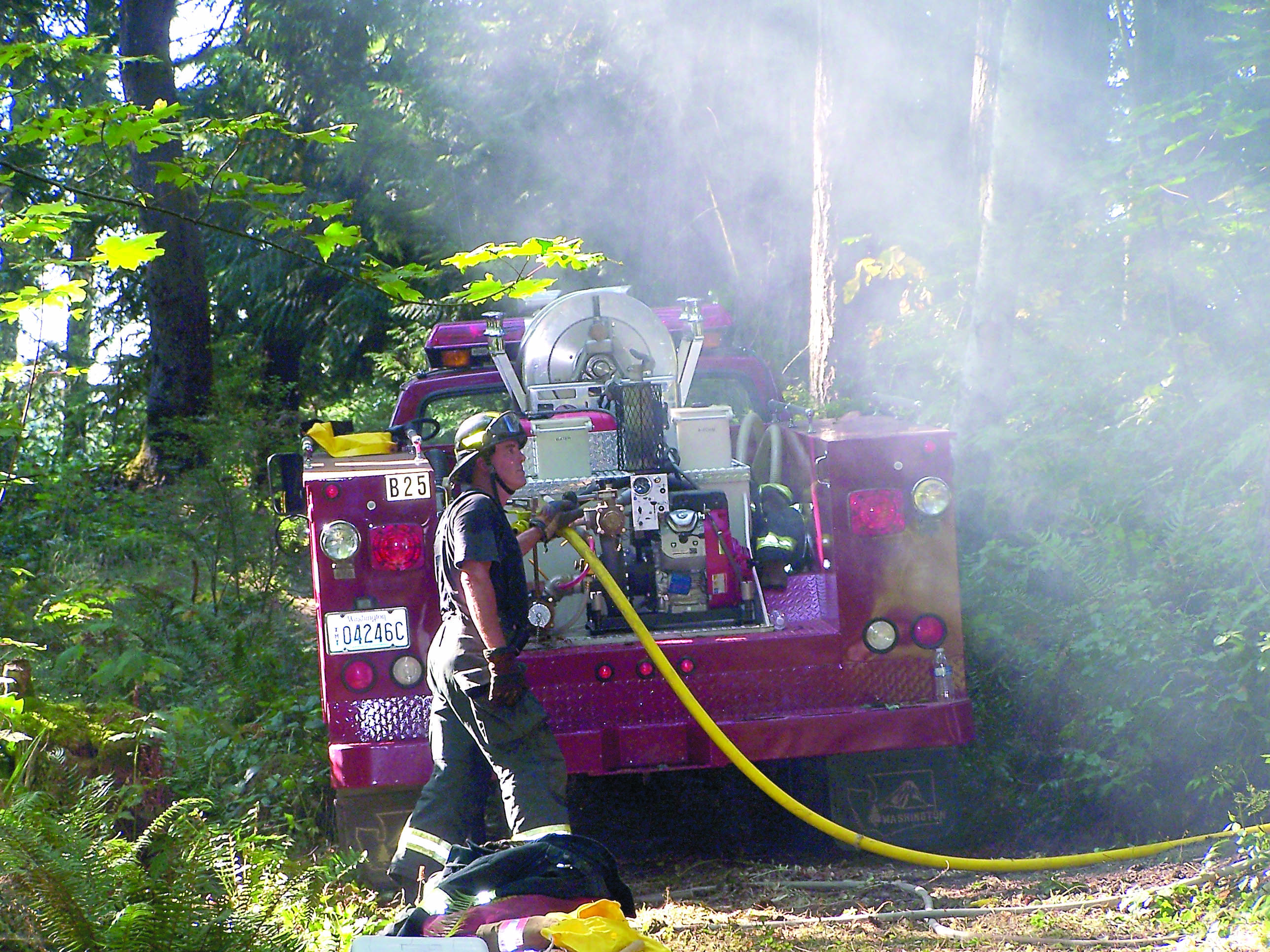 Clallam County Fire District No. 2 Firefighter Howard Parker pumps water onto a brush fire off Black Diamond Road south of Port Angeles. Clallam County Fire District No. 2