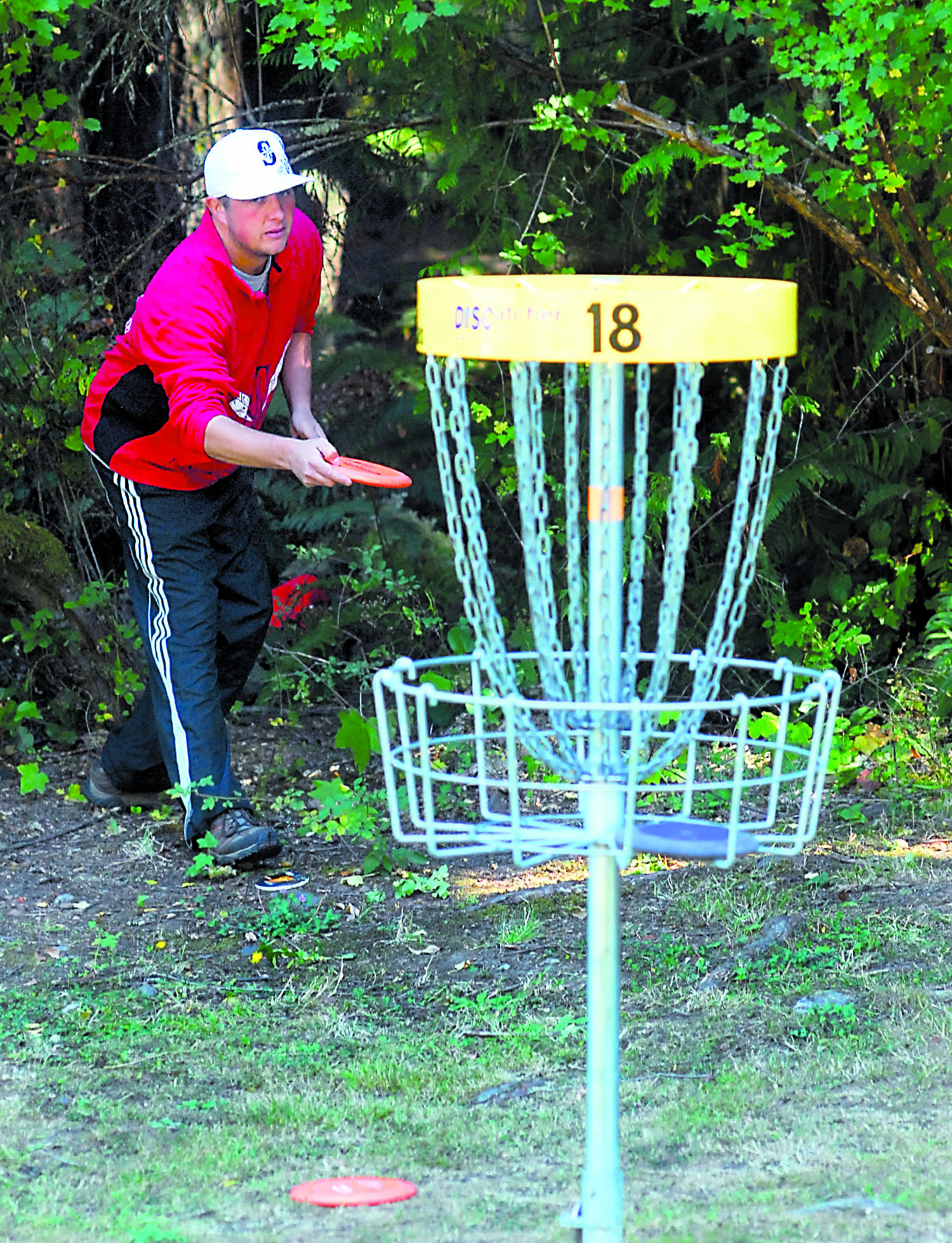 Adam Mackay of rural Port Angeles takes aim at the basket on the 18th hole of the disc golf course at Lincoln Park in Port Angeles on Saturday. Keith Thorpe/Peninsula Daily News