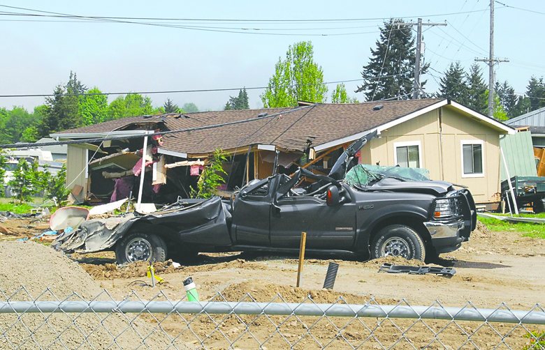 A crushed truck and a house knocked off its foundation are part of the aftermath of a bulldozer rampage May 10 in Gales Addition. Keith Thorpe/Peninsula Daily News