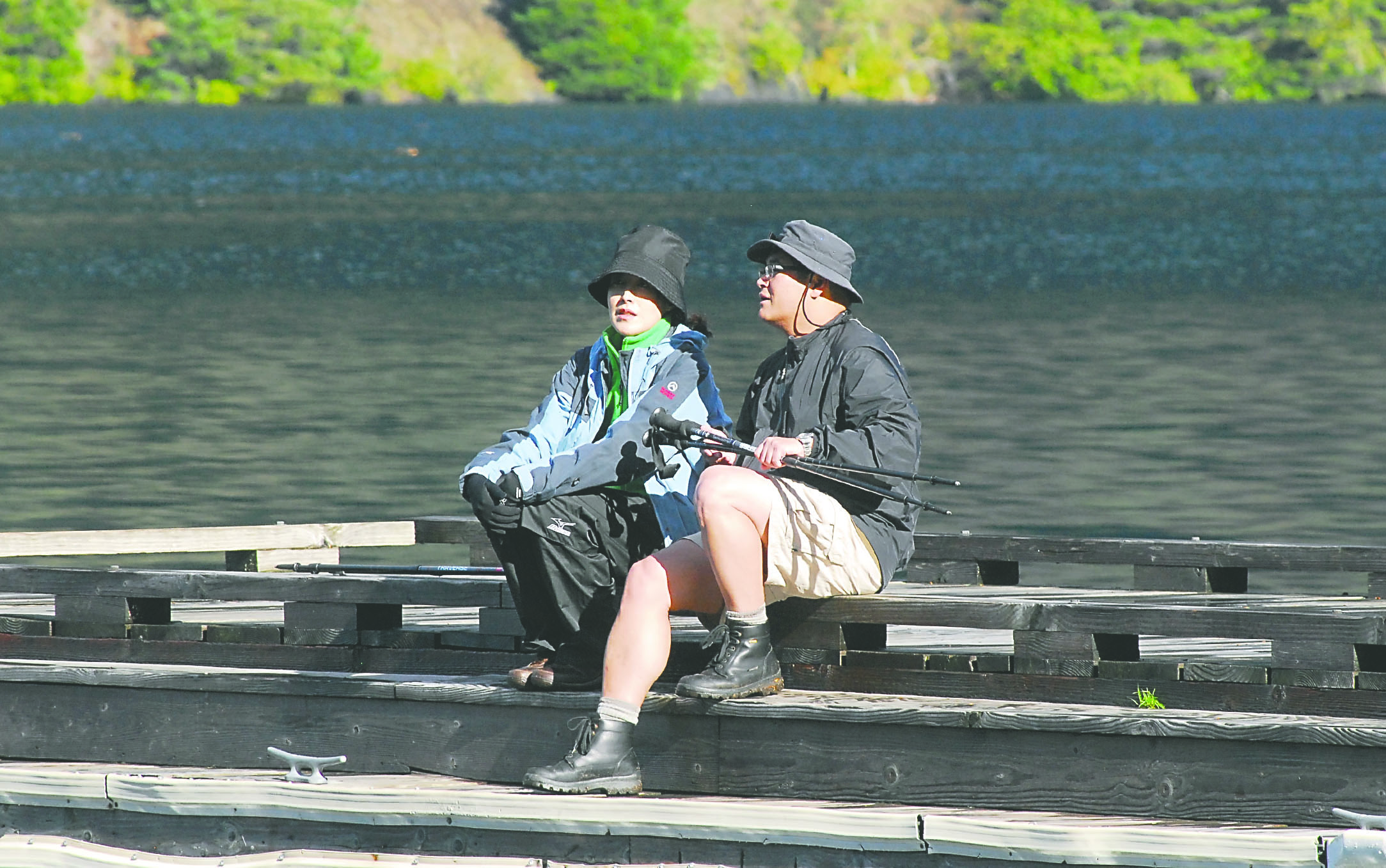 Olympic National Park visitors Grace and Henry Liu of Bellevue sit on the pier at Lake Crescent Lodge in Olympic National Park on Tuesday as they contemplate their options. The couple had hoped to go hiking