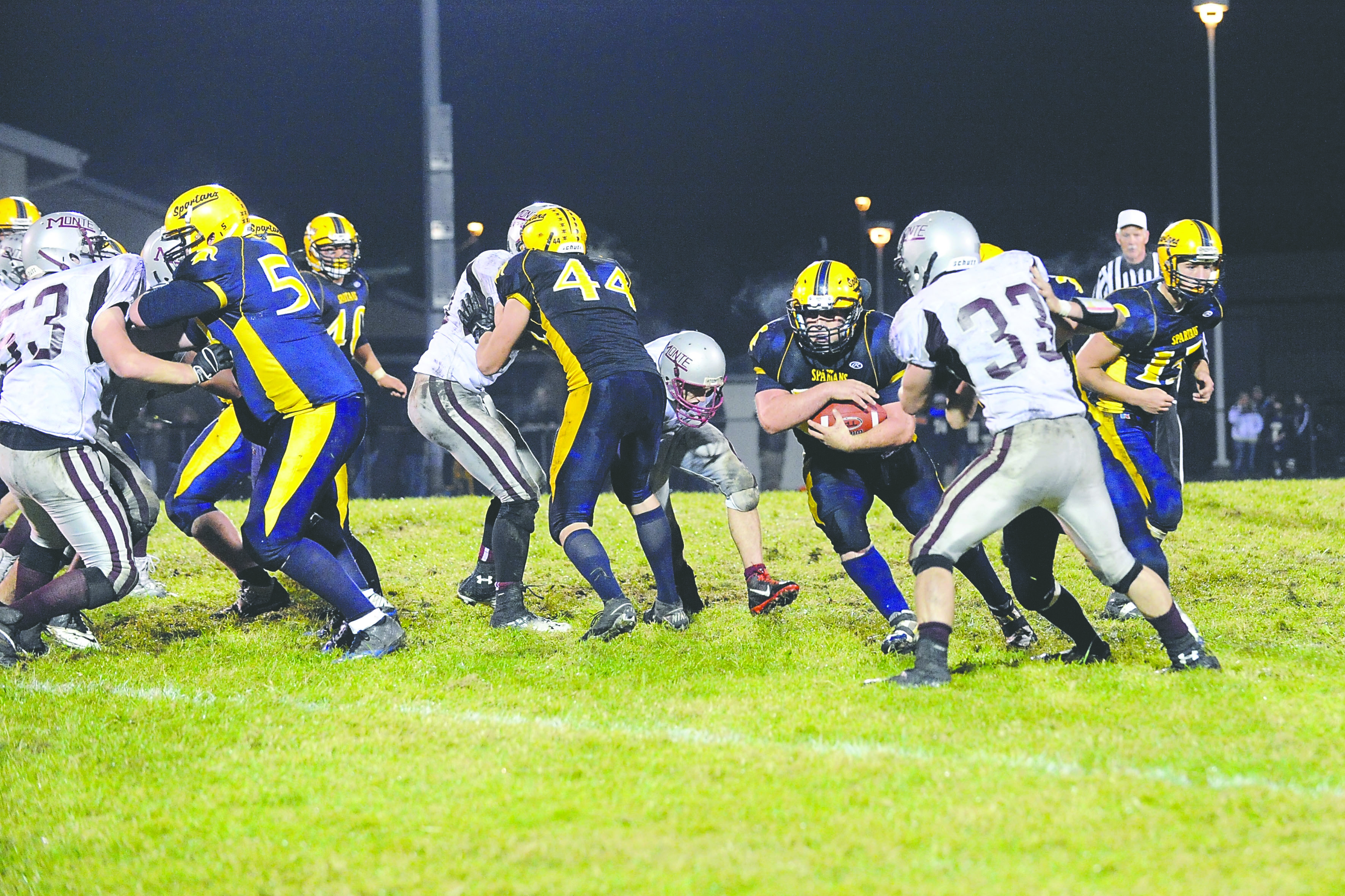 Forks running back Brett Pederson (18) finds running room behind the blocking of Tanner Robison (58) and Leo Gonzales (44) in the closing minutes of the Spartans’ win over Montesano. Photo -- Lonnie Archibald/for Peninsula Daily News