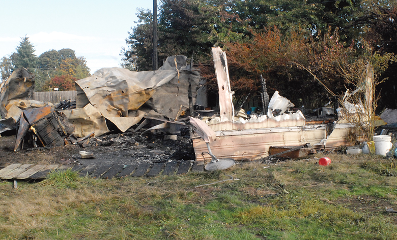 Twisted metal and charred rubble are all that remain of a mobile home at 2363 E. Fourth Ave. east of Port Angeles on Saturday morning. Keith Thorpe/Peninsula Daily News