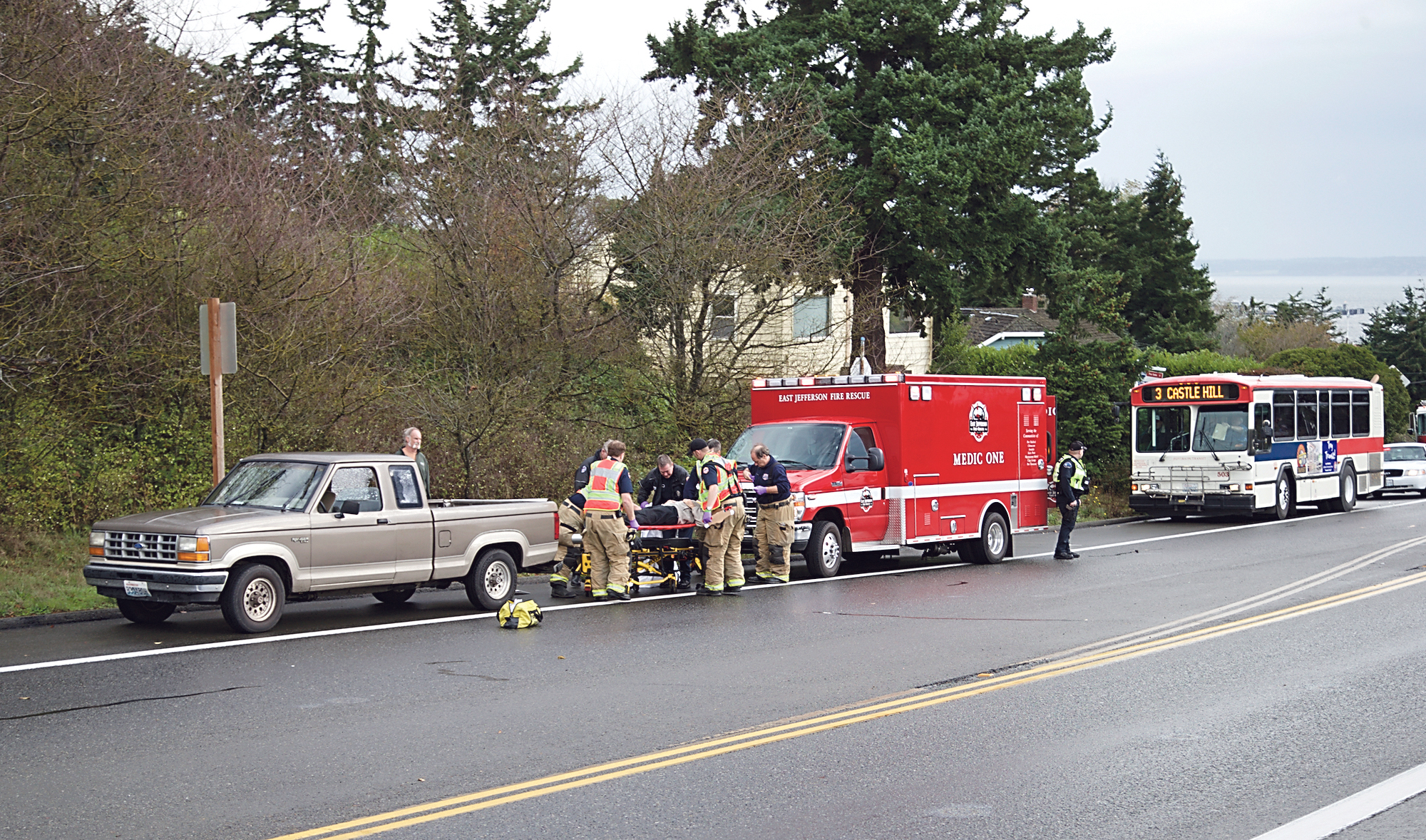 East Jefferson Fire Rescue and Port Townsend police load an injured man onto a gurney for transport to Jefferson Healthcare after a crash on Sims Way in Port Townsend on Saturday morning. Steve Mullensky/for Peninsula Daily News