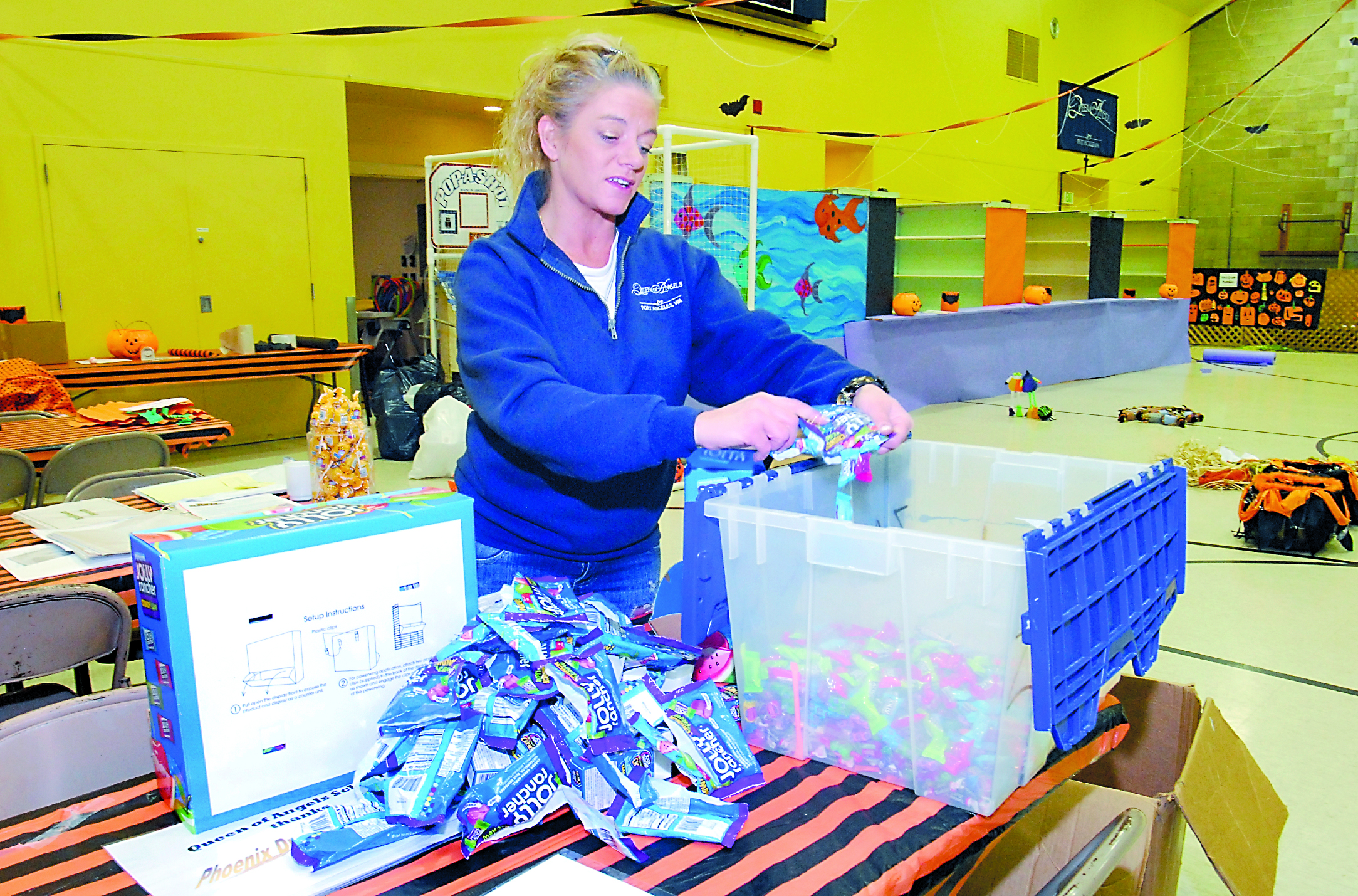 Volunteer Traci Zavodny fills a plastic bin with candy Thursday in preparation for today's Halloween Carnival in the gym of Queen of Angels School in Port Angeles. Keith Thorpe/Peninsula Daily News