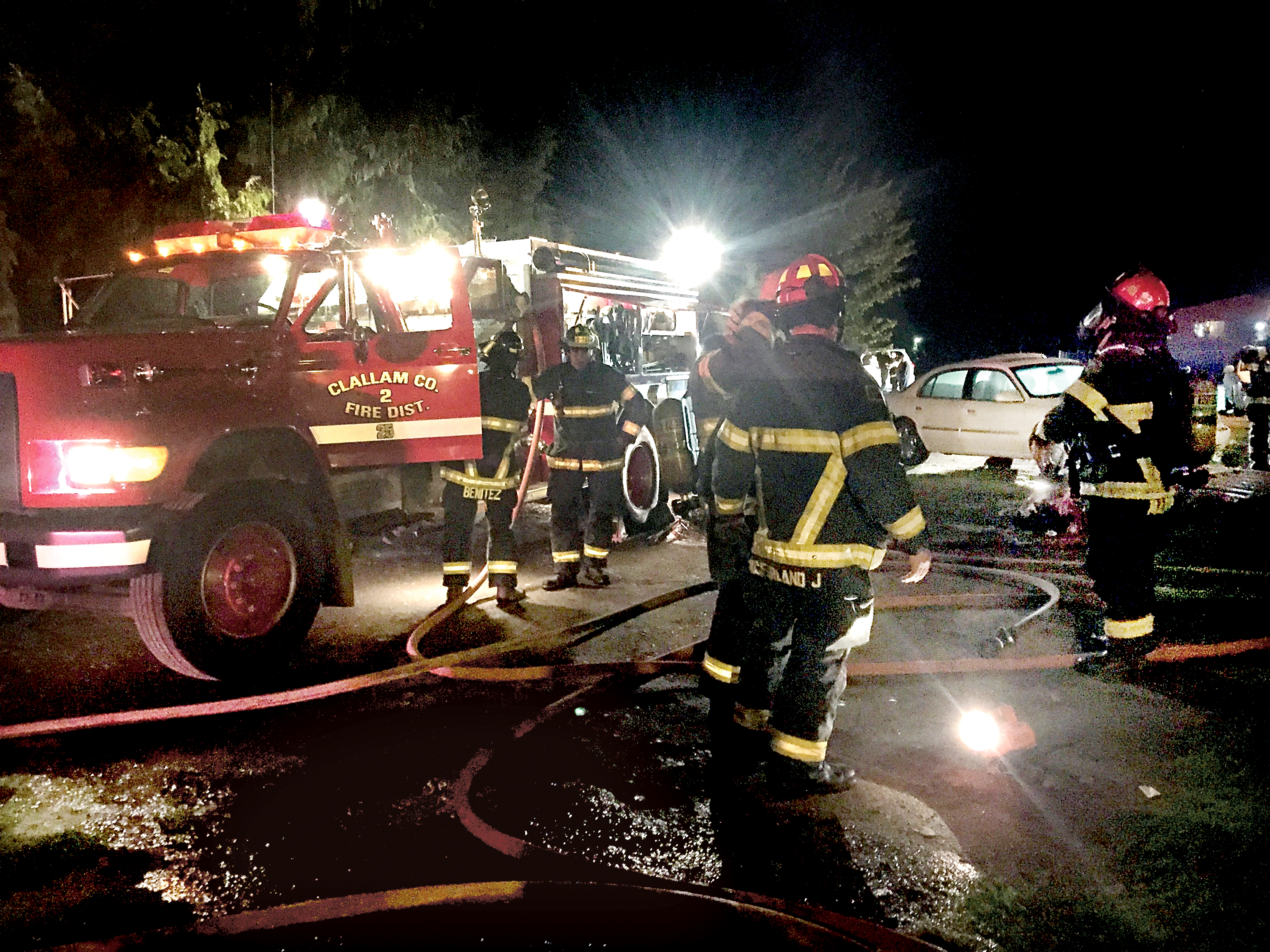 Clallam County Fire District No. 2 firefighters extinguish a fire on Ennis Creek Road that started Monday night. — Sam Phillips/Clallam County Fire District No. 2
