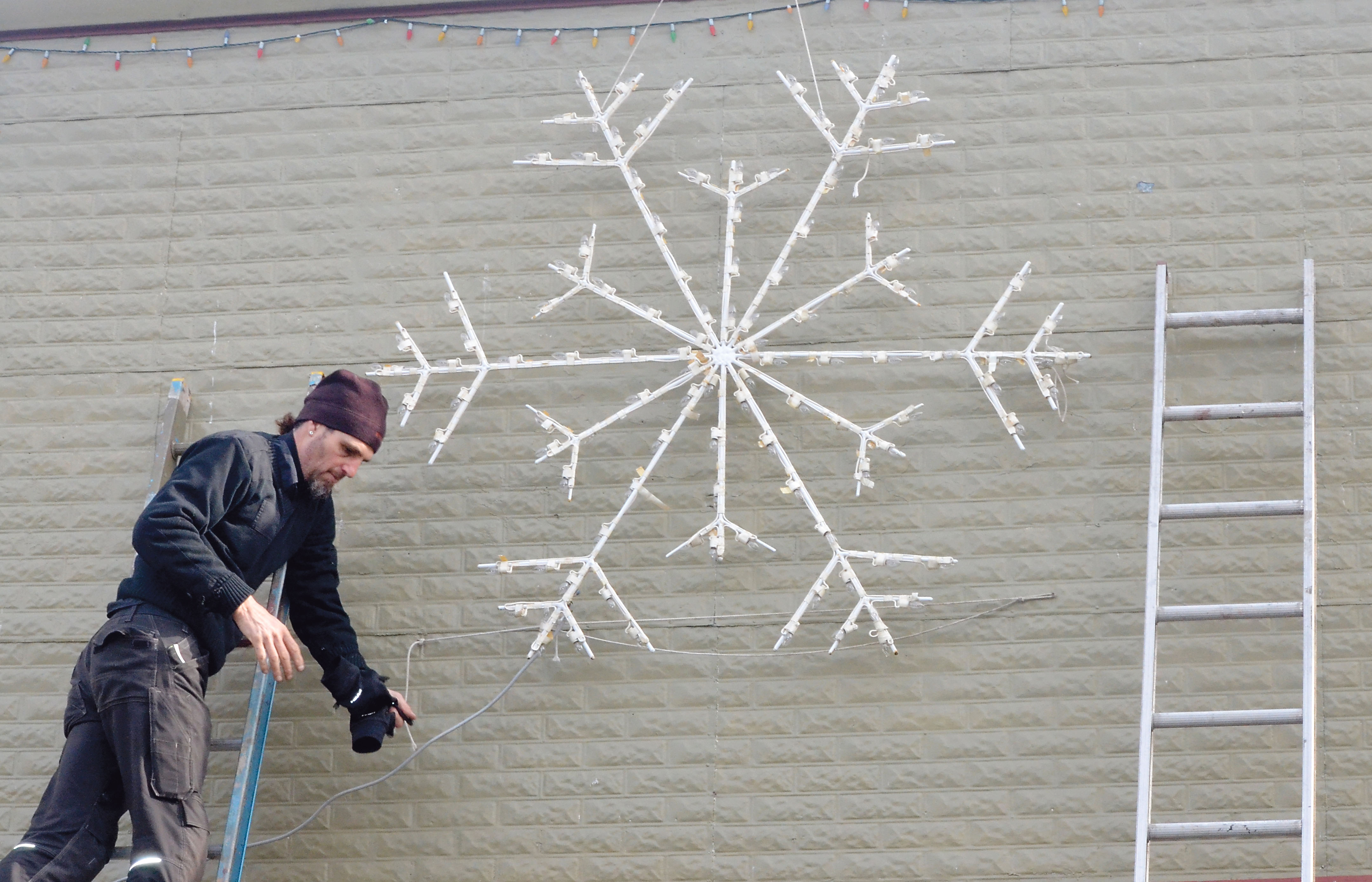 Dan Anderson installs a star on an uptown building in Port Townsend as the hanging of holiday lights commences this week.  Charlie Bermant/Peninsula Daily News