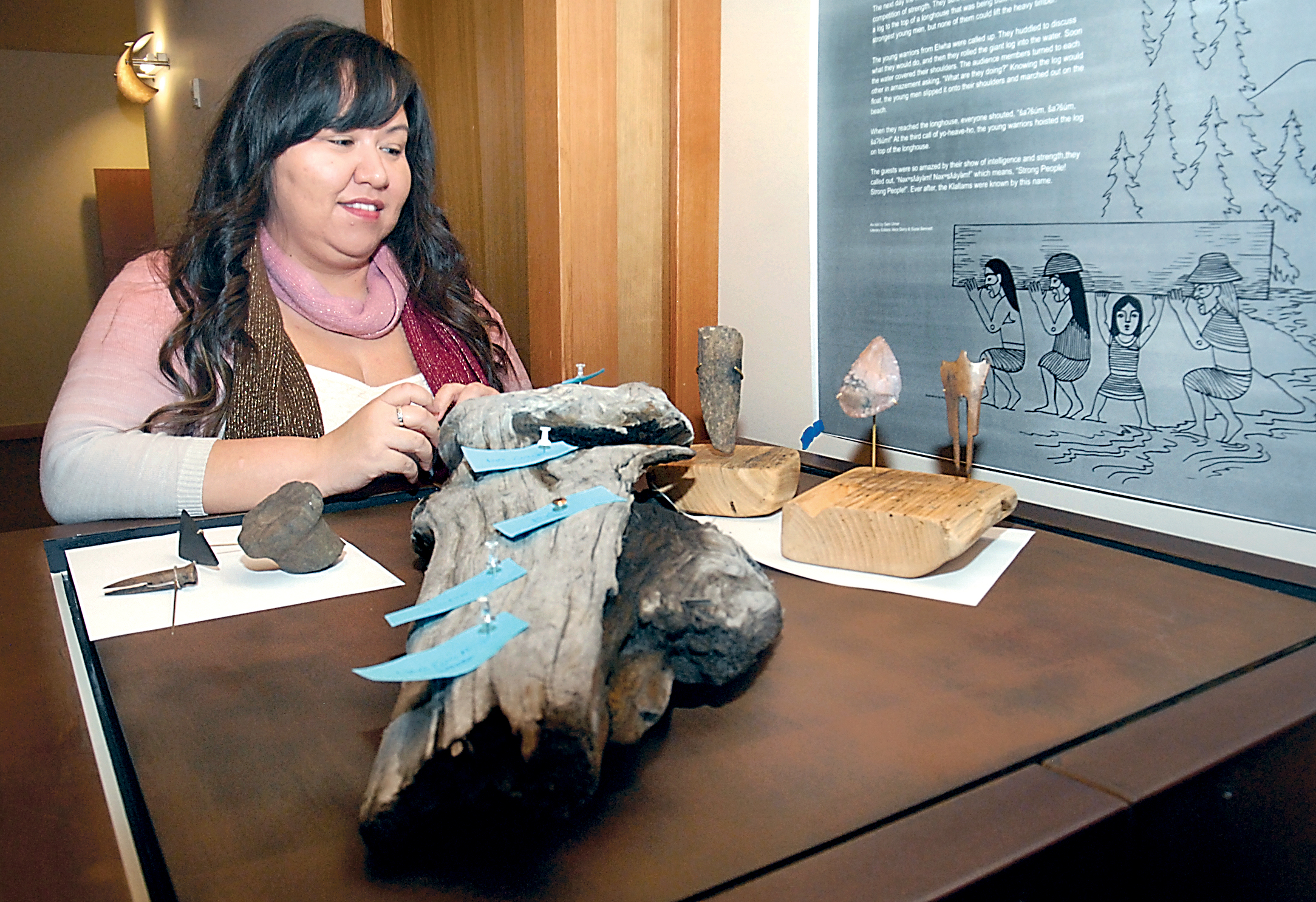Elwha Heritage Center manager Suzie Bennett looks over a selection of Klallam artifacts found at the Tse-whit-zen village site that will soon go in display at the center in Port Angeles. Included are a maul