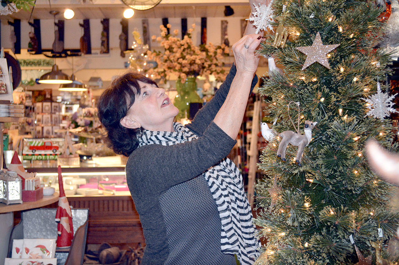 Debra Stuart, an employee at The Green Eyeshade, puts up some holiday decorations Thursday. (Mark Krulish/for Peninsula Daily News)