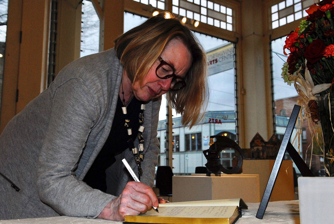 Northwind Arts Center Board President Thya Merz signs the condolence book for Jeanette Best at the center. Best, who was one of the founders of Northwind, died Thursday. (Jeannie McMacken/for Peninsula daily News)
