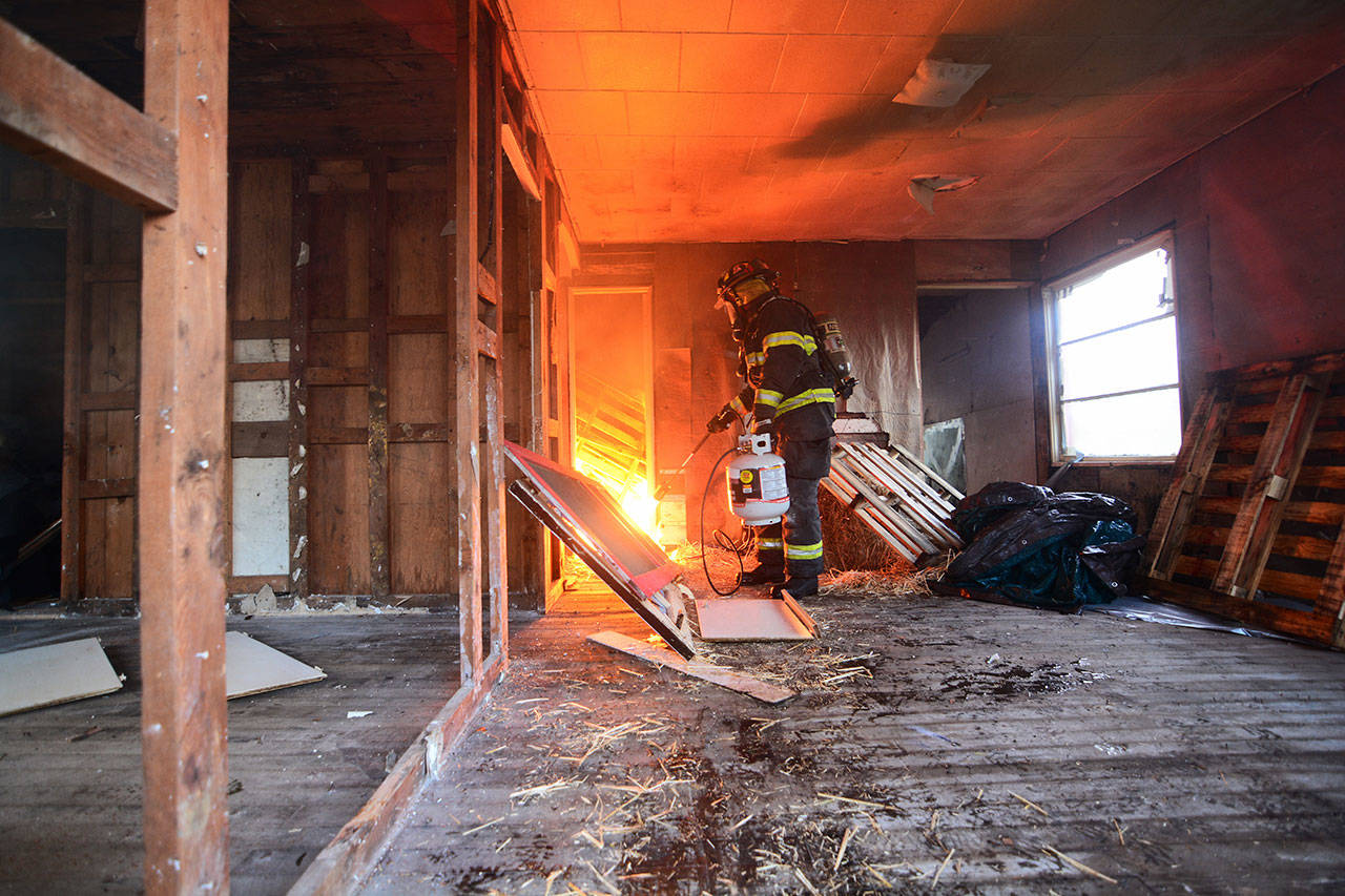 A firefighter sets fire to a building during a training day in Port Angeles on Sunday. (Jesse Major/Peninsula Daily News)