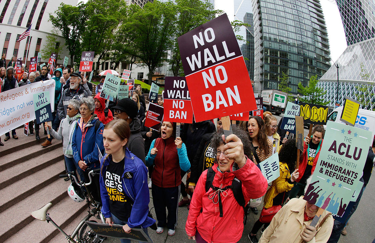 Protesters wave signs and chant during a demonstration against President Donald Trump’s revised travel ban outside a federal courthouse in Seattle on May 15. (Ted S. Warren/The Associated Press)