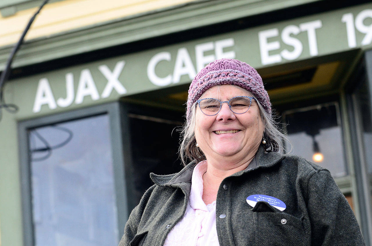 Betsy Davis, executive director of the Northwest School of Wooden Boatbuilding, stands next to the Ajax Cafe, which it is hoped will reopen this spring after a community effort raised funds that allowed the school to purchase the property. (Jesse Major/Peninsula Daily News)